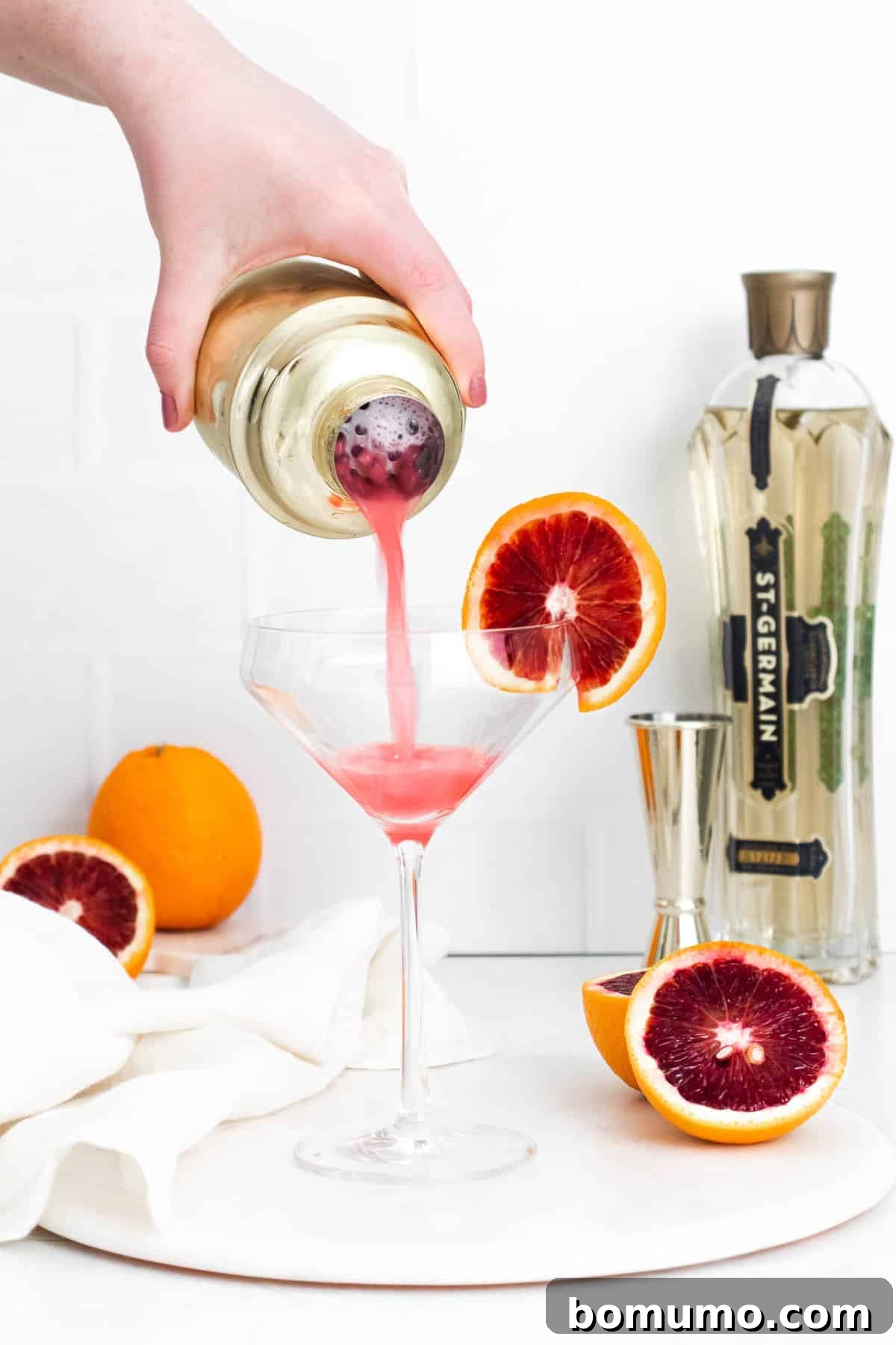 Cocktail being strained into a coupe glass. Finishing the Blood Orange Gin Fizz.