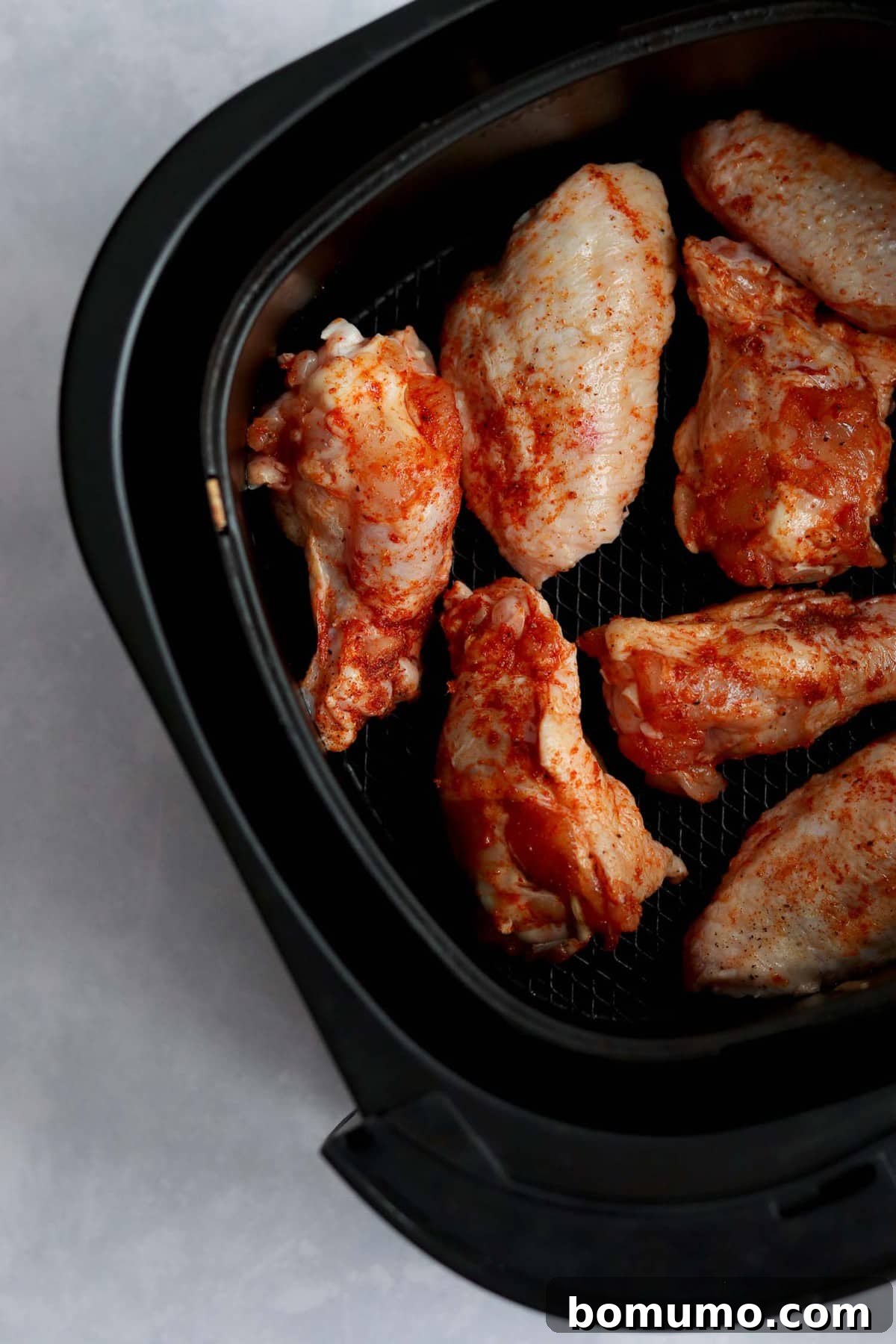 Uncooked wings in air fryer.