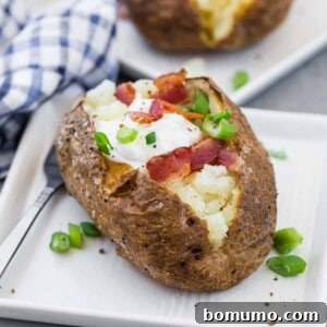 A potato split open and topped with sour cream, bacon, and green onions.