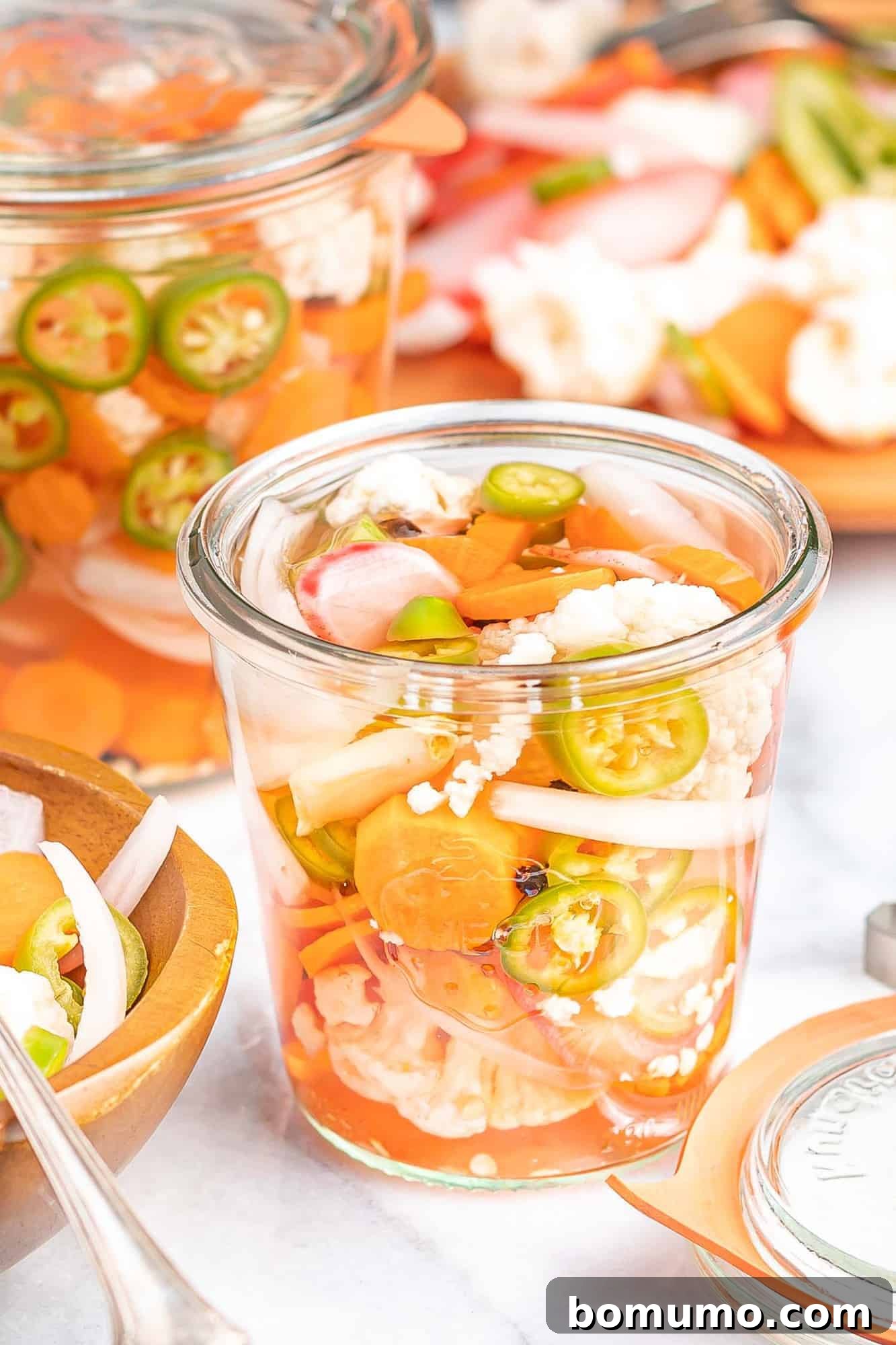 Mixed vegetables in a glass jar with liquid, showcasing the vibrant colors of carrots, cauliflower, radishes, and jalapeños.