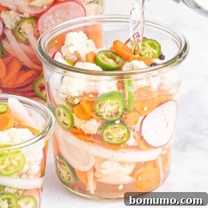 Vegetables in a jar with liquid being poured into it, capturing the essence of the pickling process.