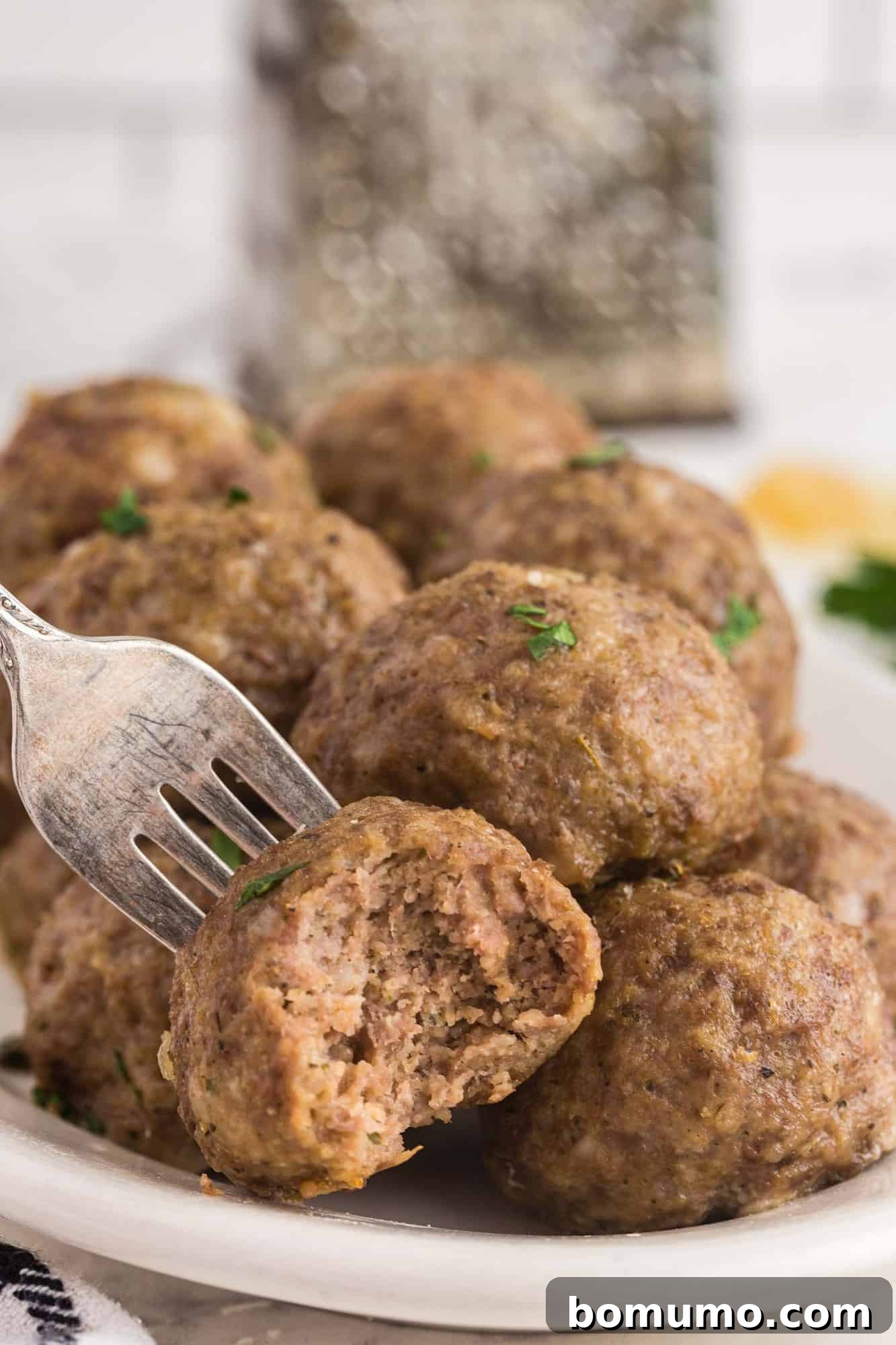 A close-up of a delicious meatball with a bite taken out, revealing its juicy interior.
