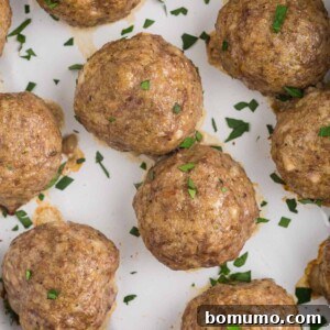 Overhead view of baked meatballs without sauce, sprinkled with parsley.