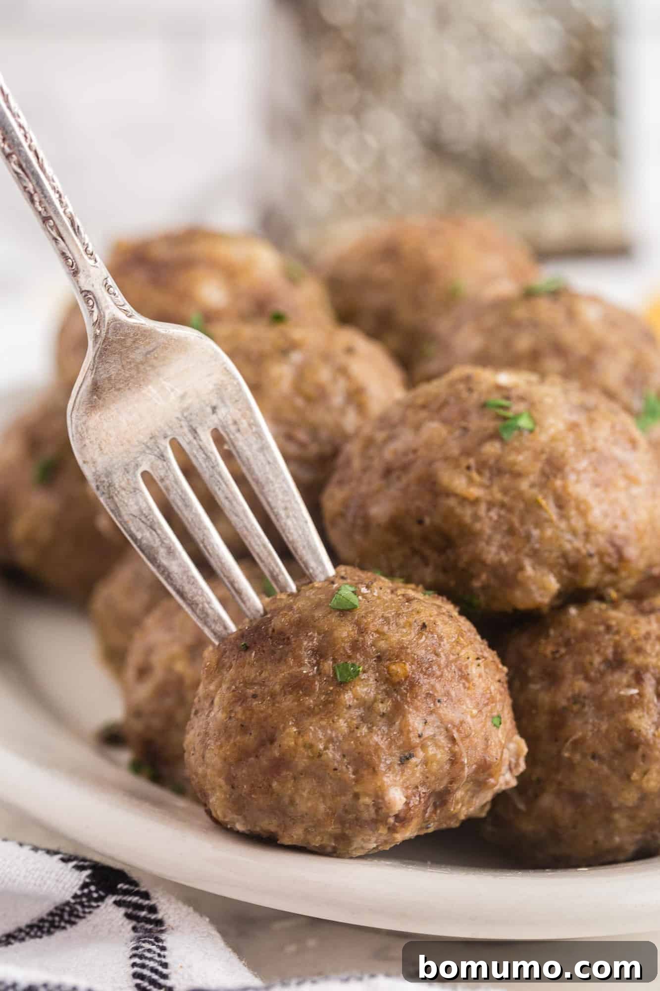 A single perfectly cooked meatball balanced on a fork, ready to be enjoyed.
