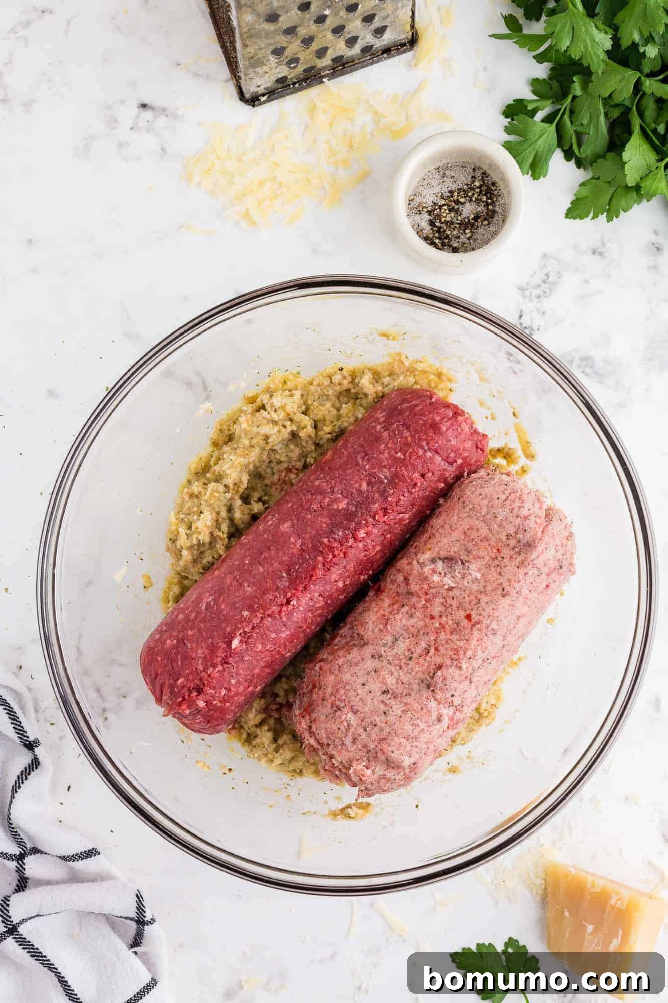 All meatball ingredients, including ground meat, spices, eggs, and the soaked breadcrumb mixture, in a bowl before mixing.