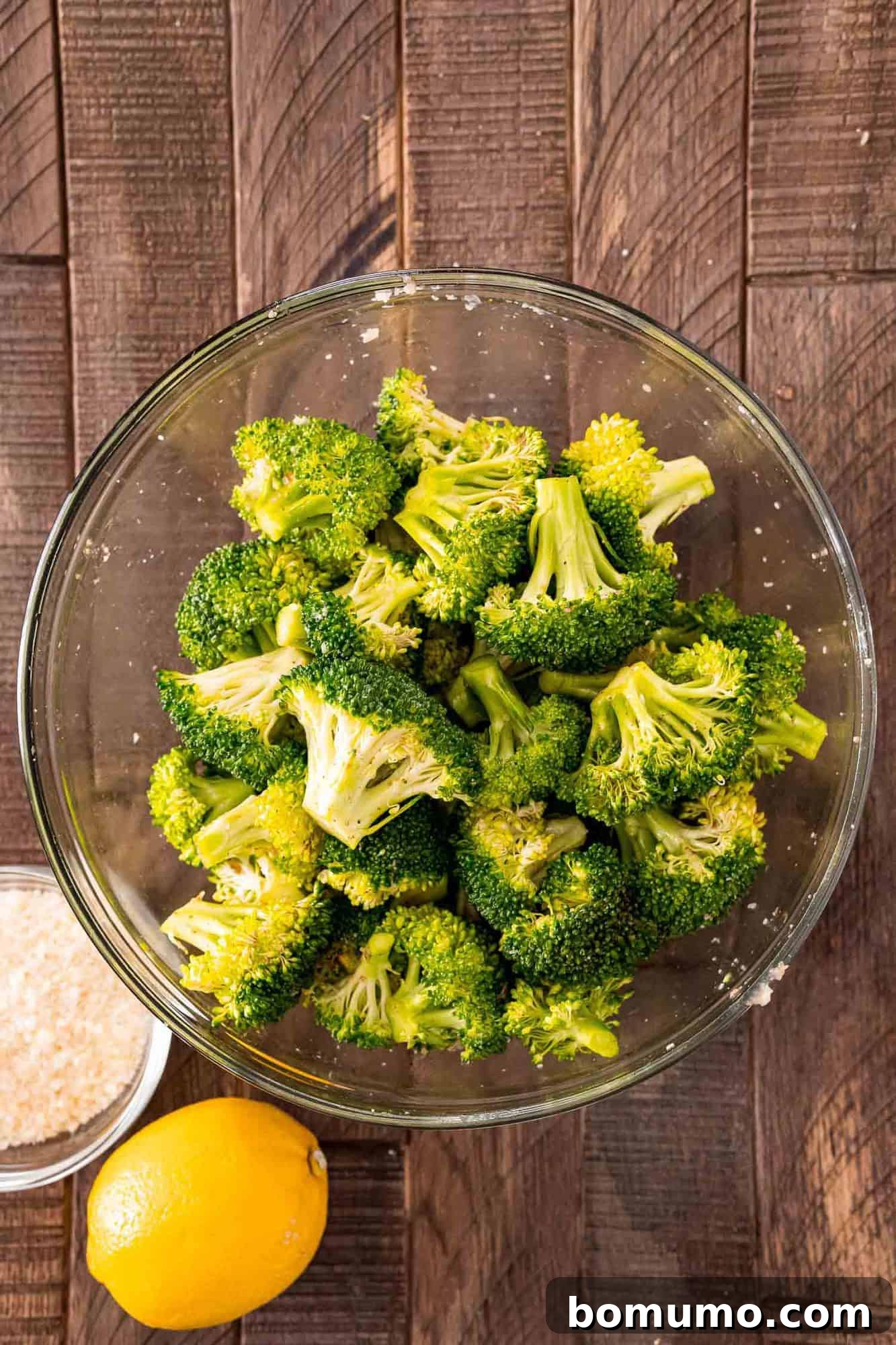 Crispy Lemon-Parmesan Roasted Broccoli 5 Fresh broccoli florets coated in olive oil and seasonings, resting in a pristine white mixing bowl.