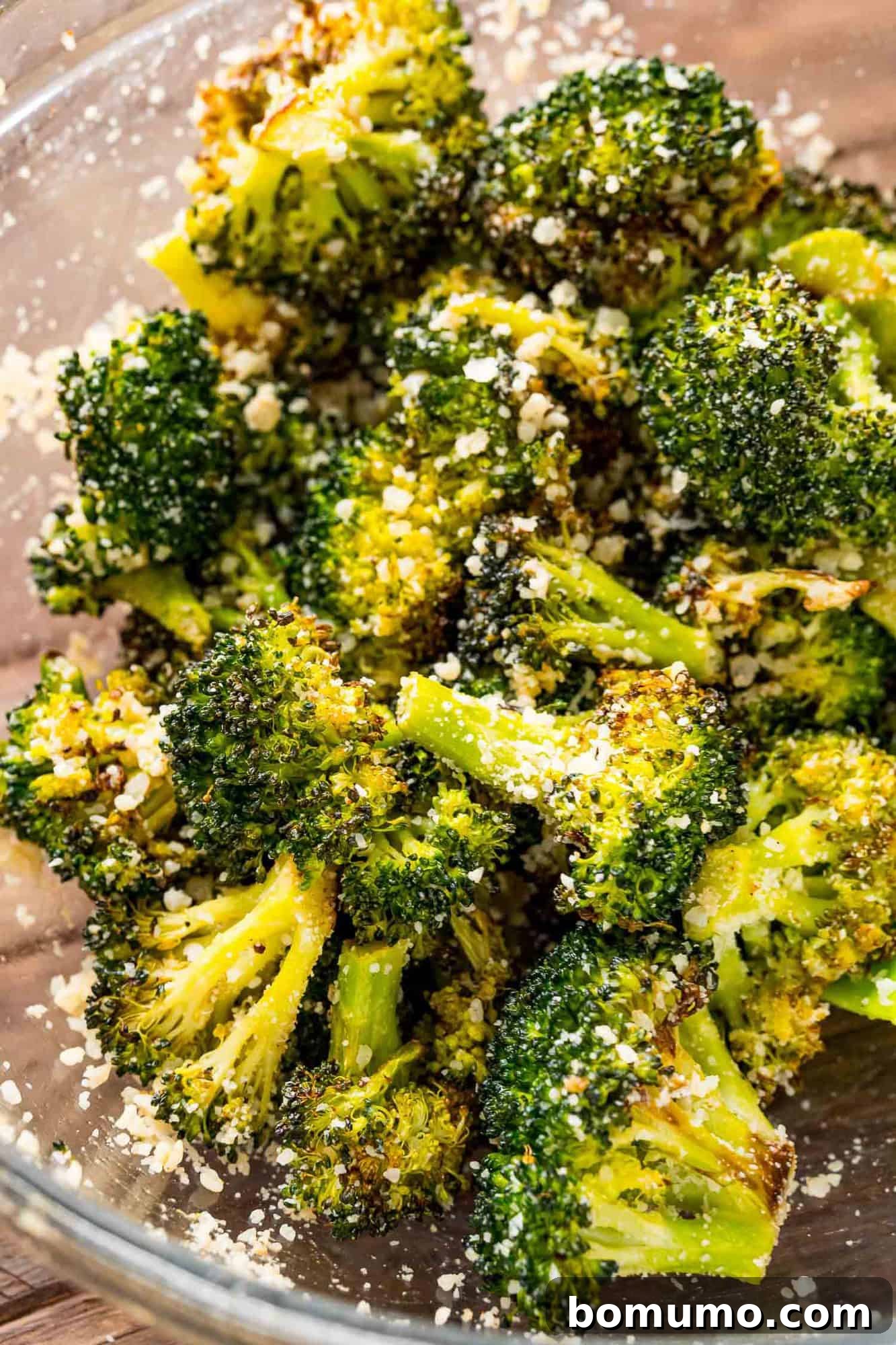 Crispy Lemon-Parmesan Roasted Broccoli 8 Freshly roasted broccoli being tossed in a bowl with grated Parmesan cheese, ready to serve.