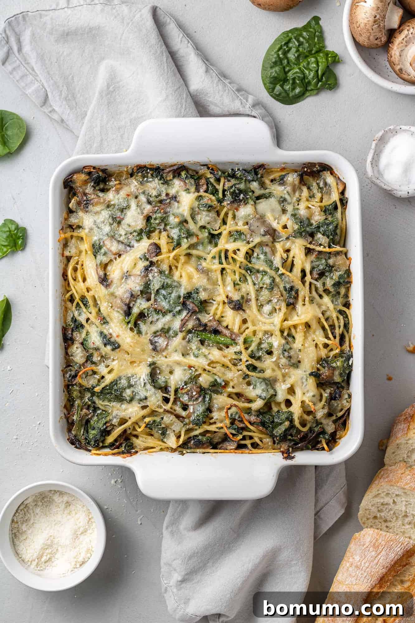 Cheesy Spinach Baked Spaghetti 2 Baked spaghetti with spinach and mushrooms in a square white baking dish.