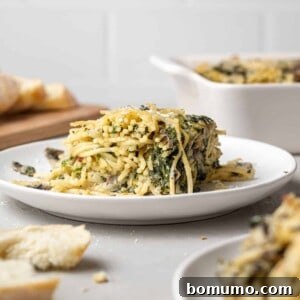 Cheesy Spinach Baked Spaghetti 13 Baked spaghetti with spinach on a small round white plate.