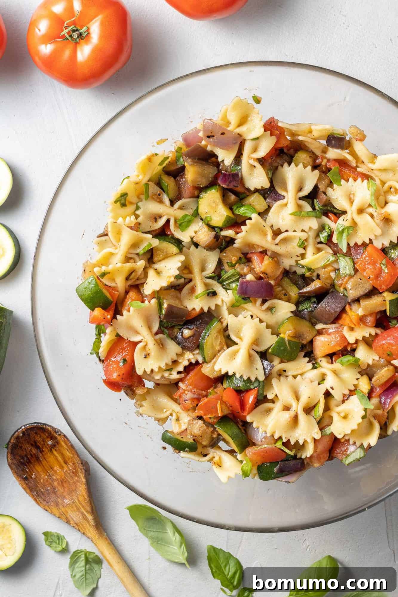 Pasta salad in a clear glass mixing bowl.