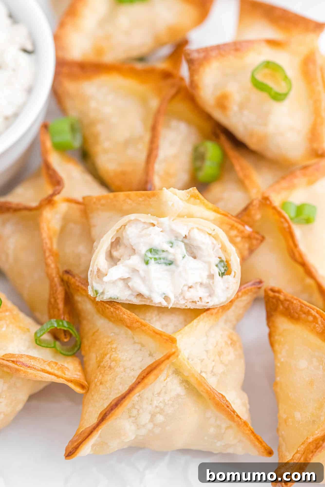 Crab rangoon on a plate with green onions, ready to be served.