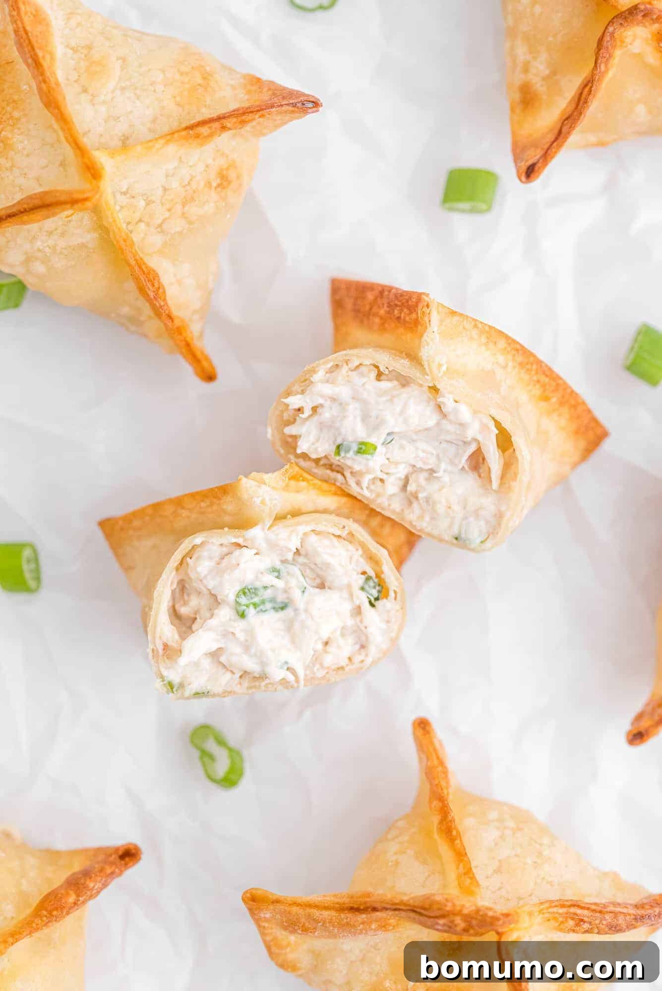 Overhead view of several air fryer crab wontons garnished with fresh green onions.