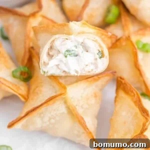 Air fryer crab rangoons, one split open to show creamy filling.