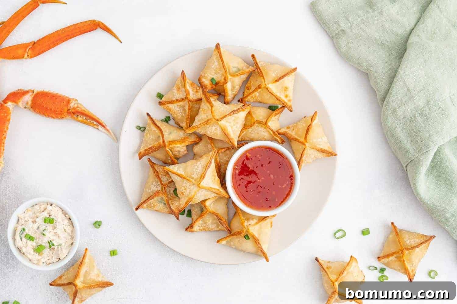 A beautifully arranged plate of air fryer crab rangoon with a small bowl of sweet chili sauce for dipping.