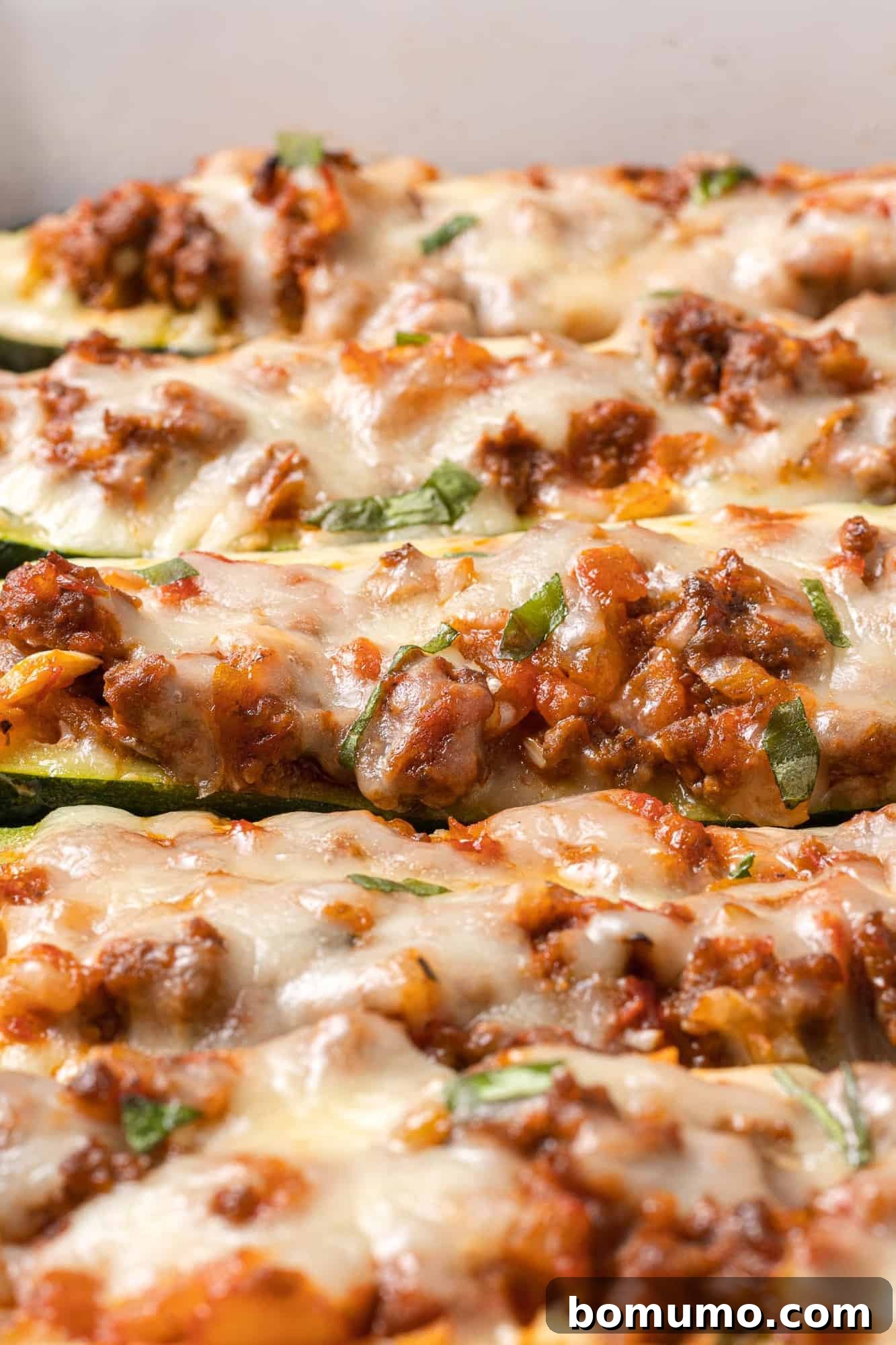 Close up of stuffed zucchini with melted cheese on top.