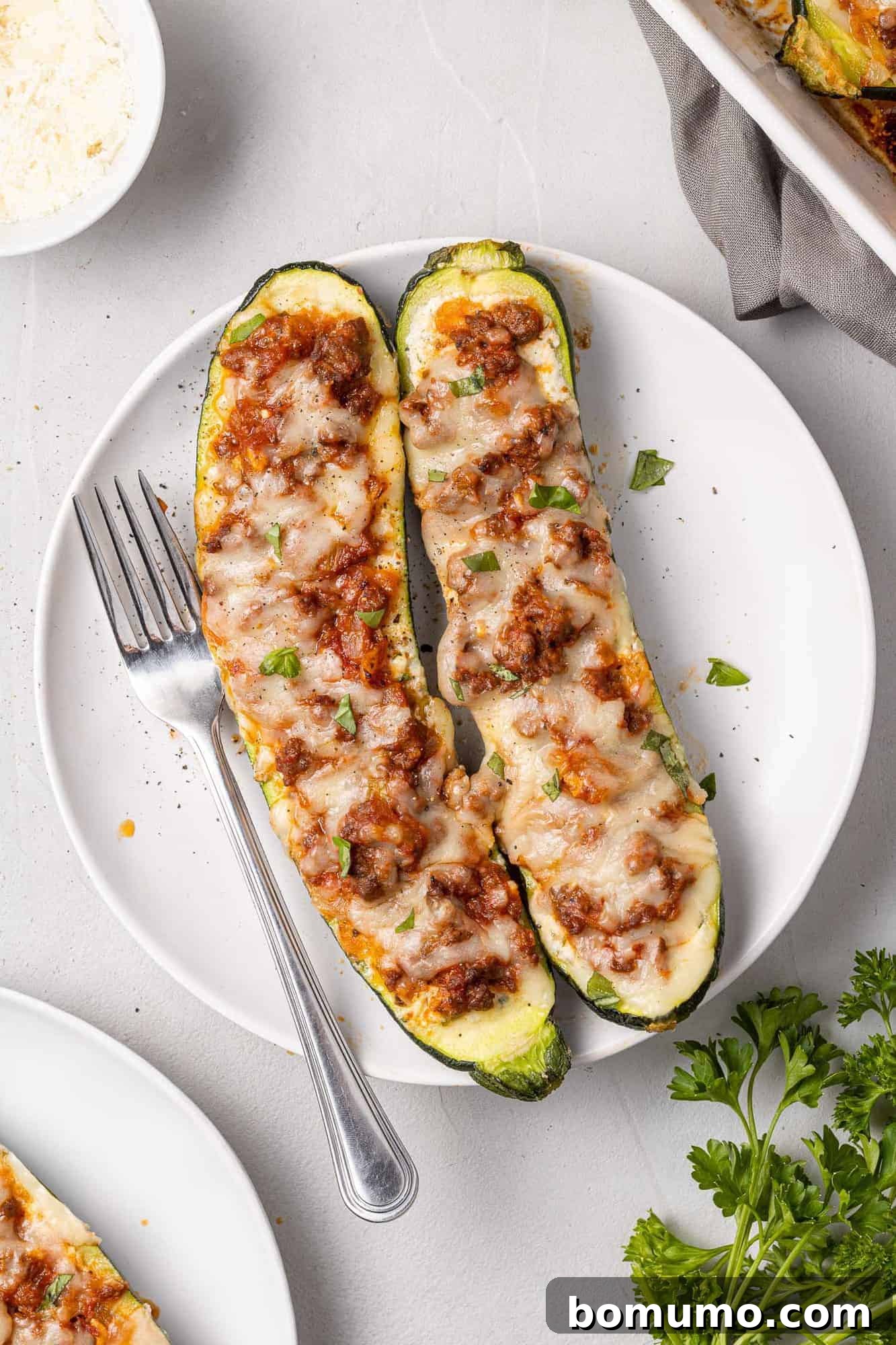 Two lasagna boats on a plate with a fork.