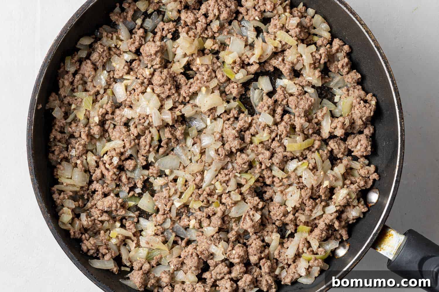 Browned ground meat and onions in a black skillet.