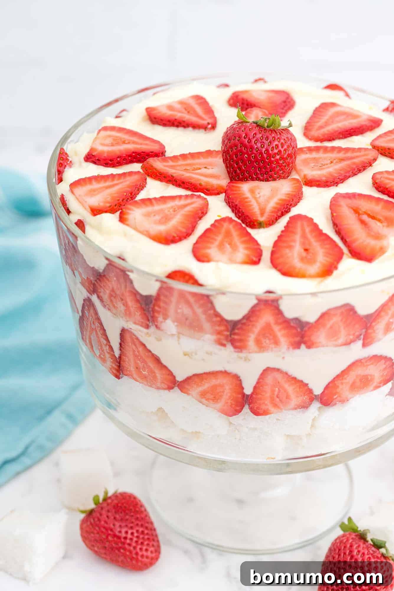 Effortless Strawberry Trifle 12 A full, complete strawberry trifle, beautifully layered with strawberries, angel food cake, and whipped cream pudding mixture, showcased in a clear glass bowl.