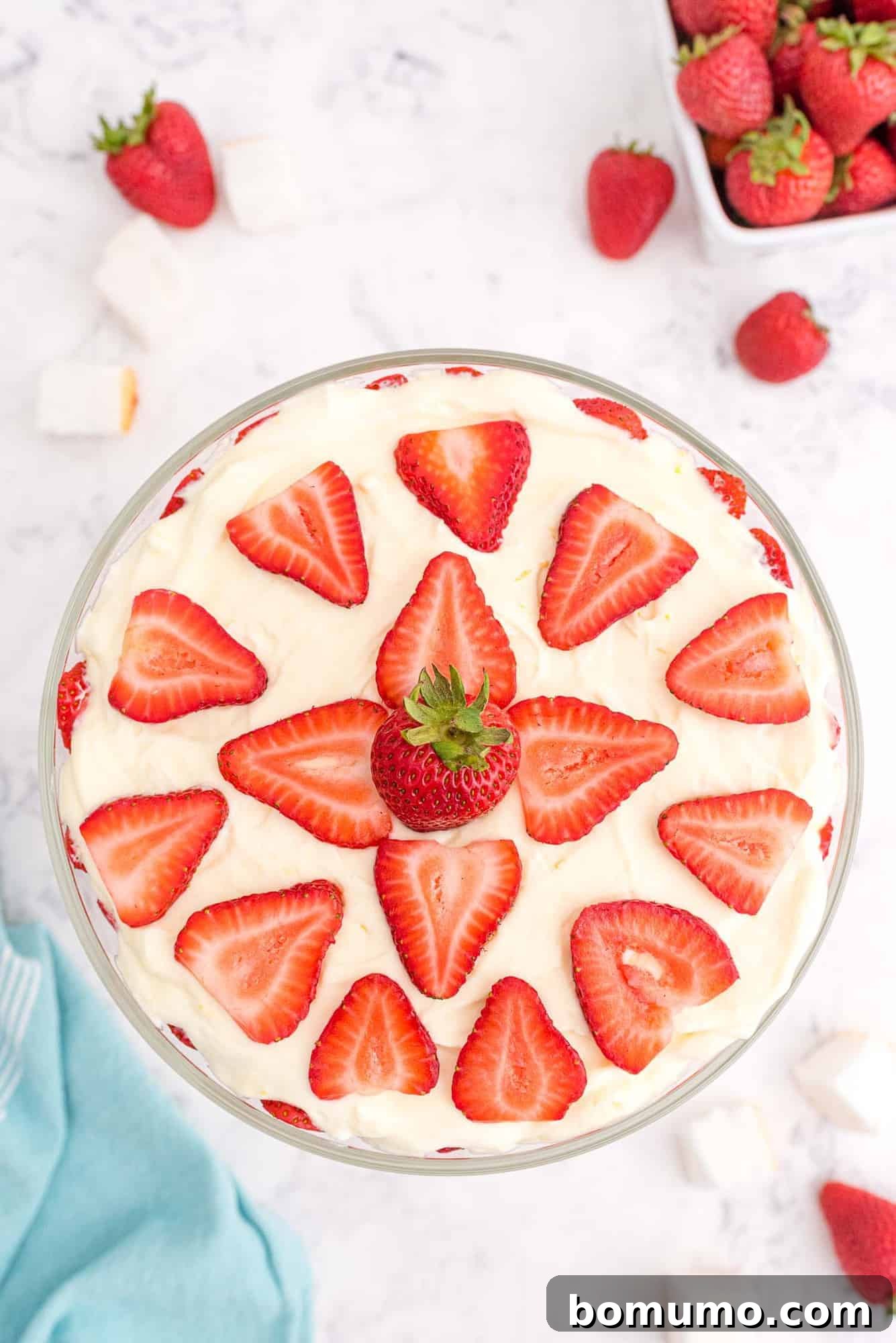 Effortless Strawberry Trifle 3 Strawberry trifle presented from an aerial view, with an inviting decorative topping of fresh strawberry slices and a hint of mint.