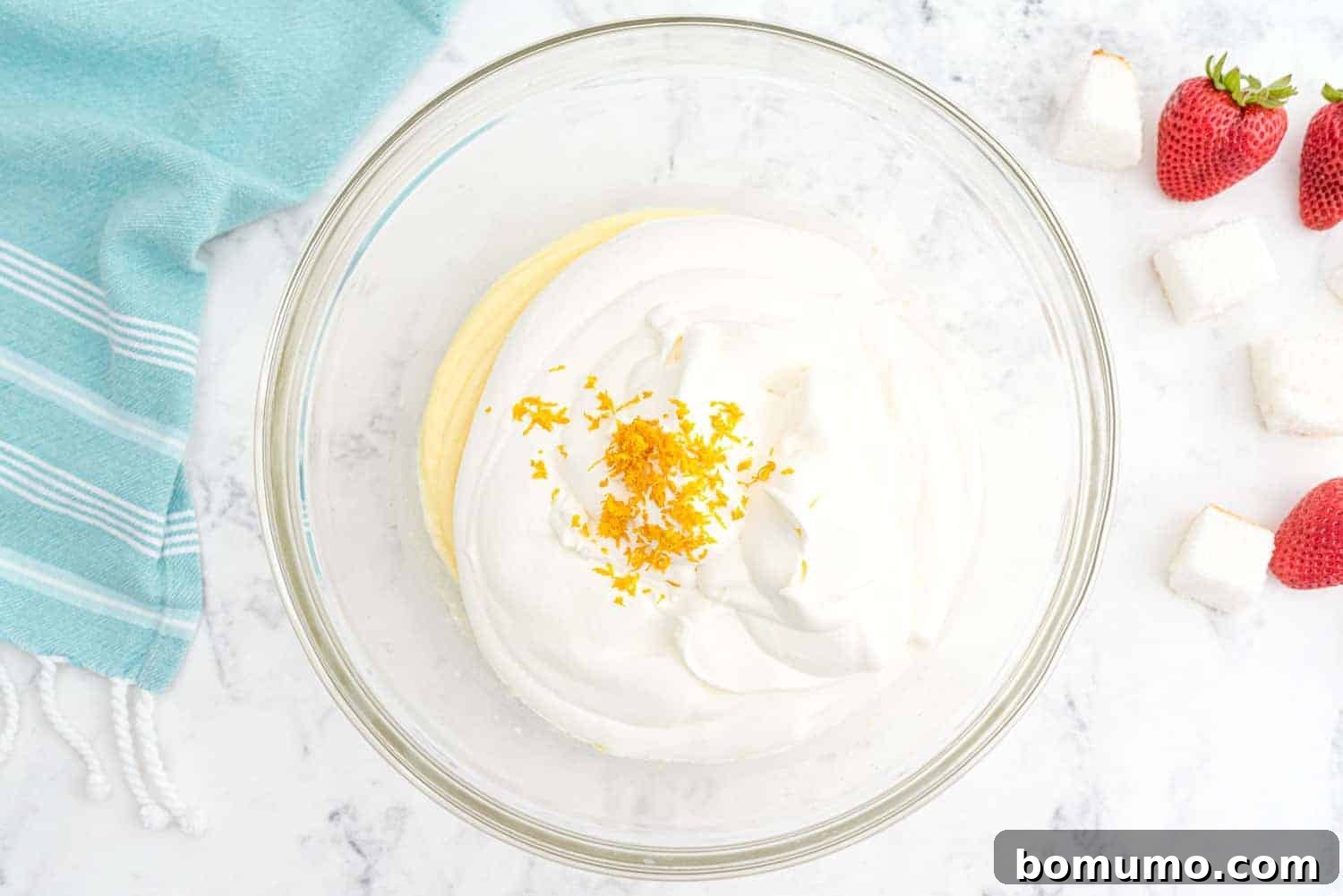 Effortless Strawberry Trifle 9 A perfectly blended mixture of pudding, whipped cream, and orange zest in a clear bowl, displaying its light and fluffy consistency.