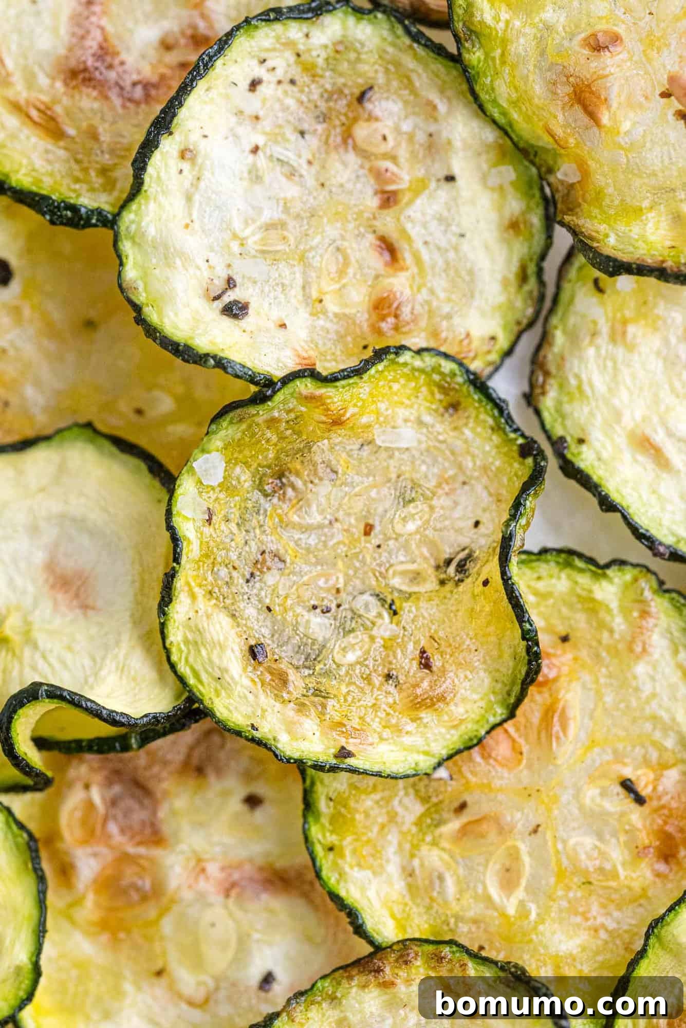 Overhead view of crispy air fryer zucchini chips layered on top of each other, showcasing their golden-brown texture.