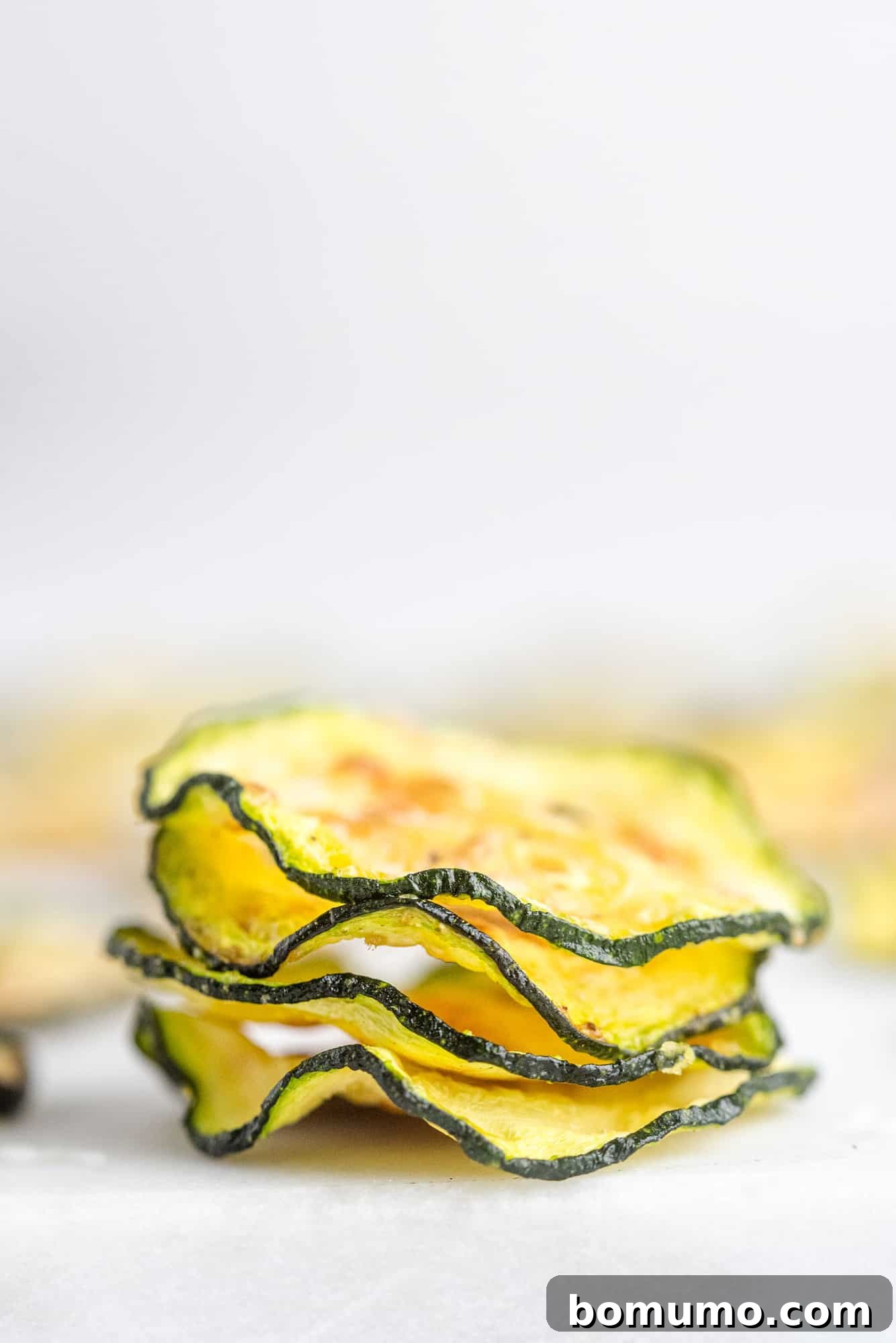 Stacked up air fryer zucchini chips, highlighting their appealing crispy texture and golden color.