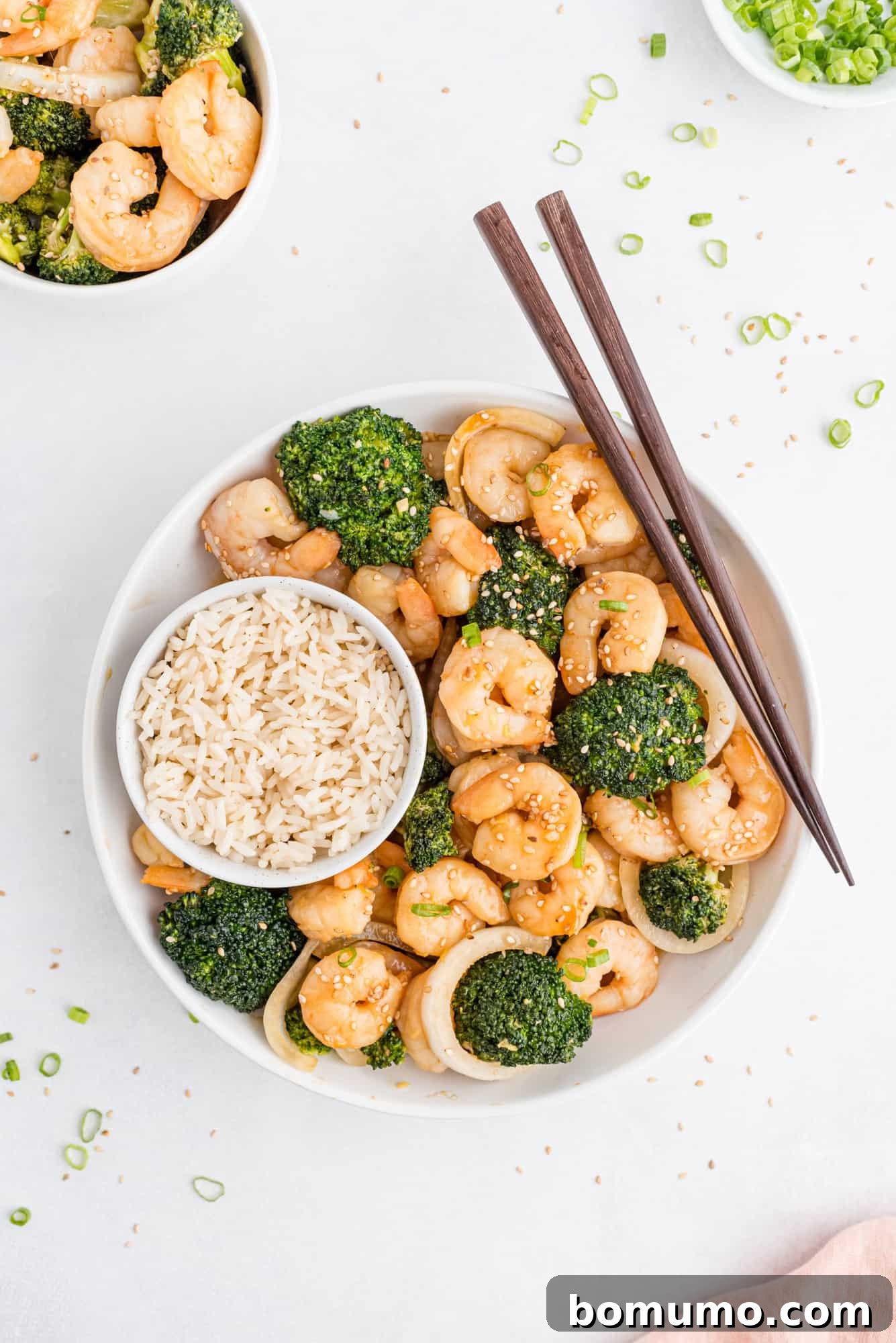 A vibrant bowl of shrimp and broccoli stir-fry with rice, artfully presented with chopsticks, ready to be enjoyed.