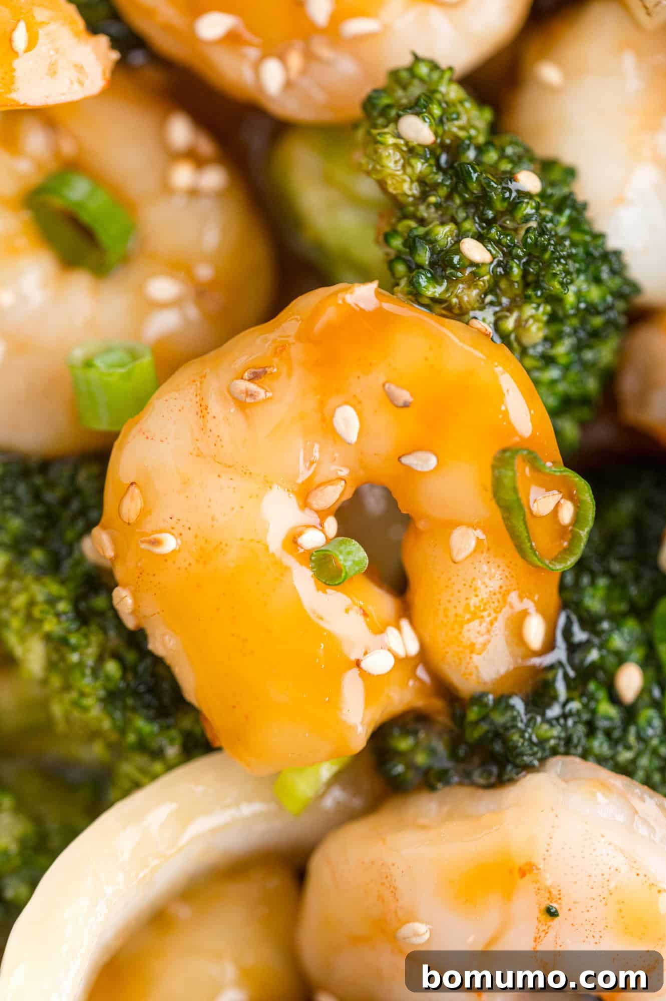 Close-up of perfectly cooked shrimp coated in a rich brown sauce, nestled alongside vibrant green broccoli florets.