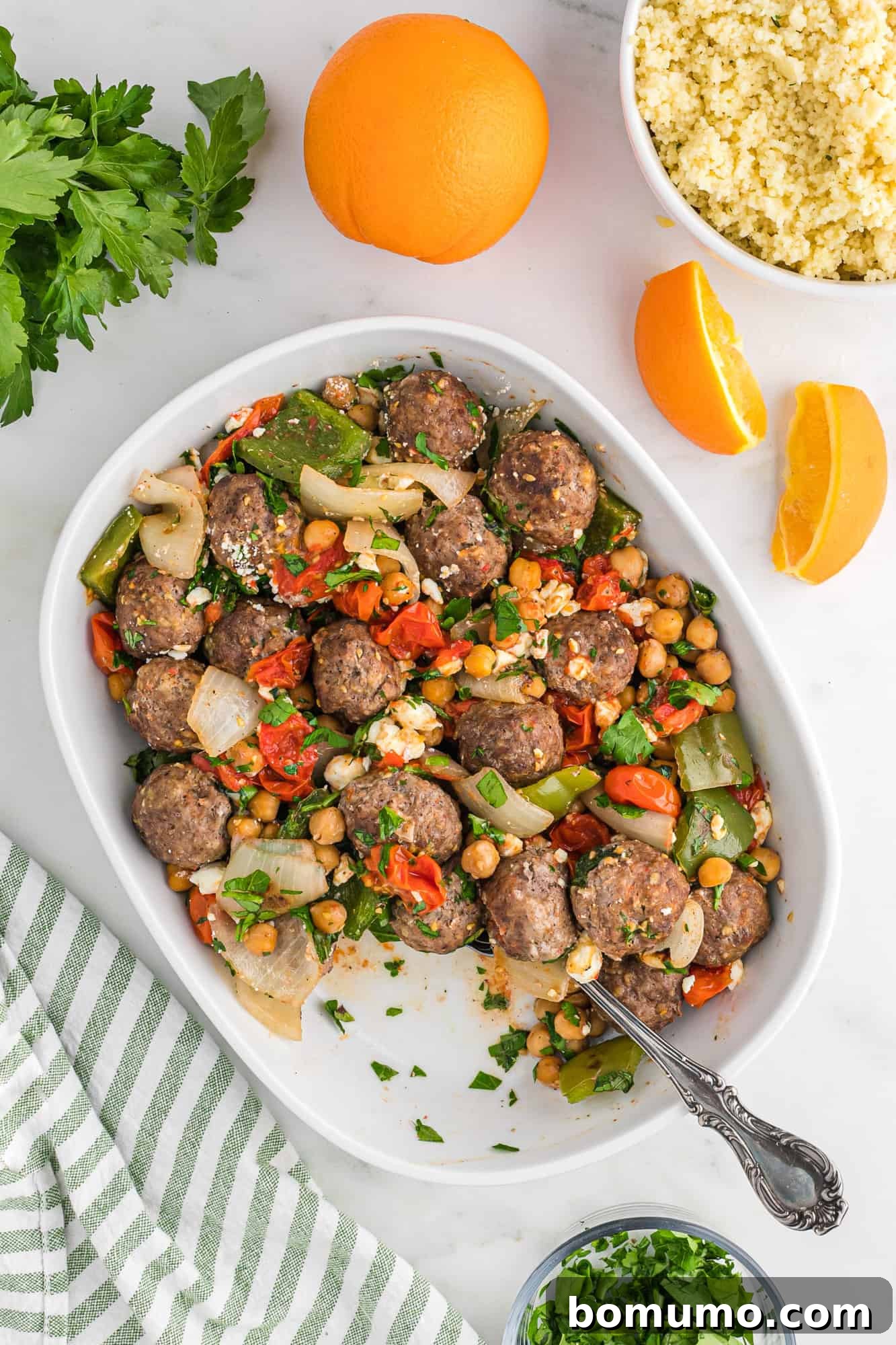 Finished Moroccan meatball recipe presented in a large white casserole dish, garnished.
