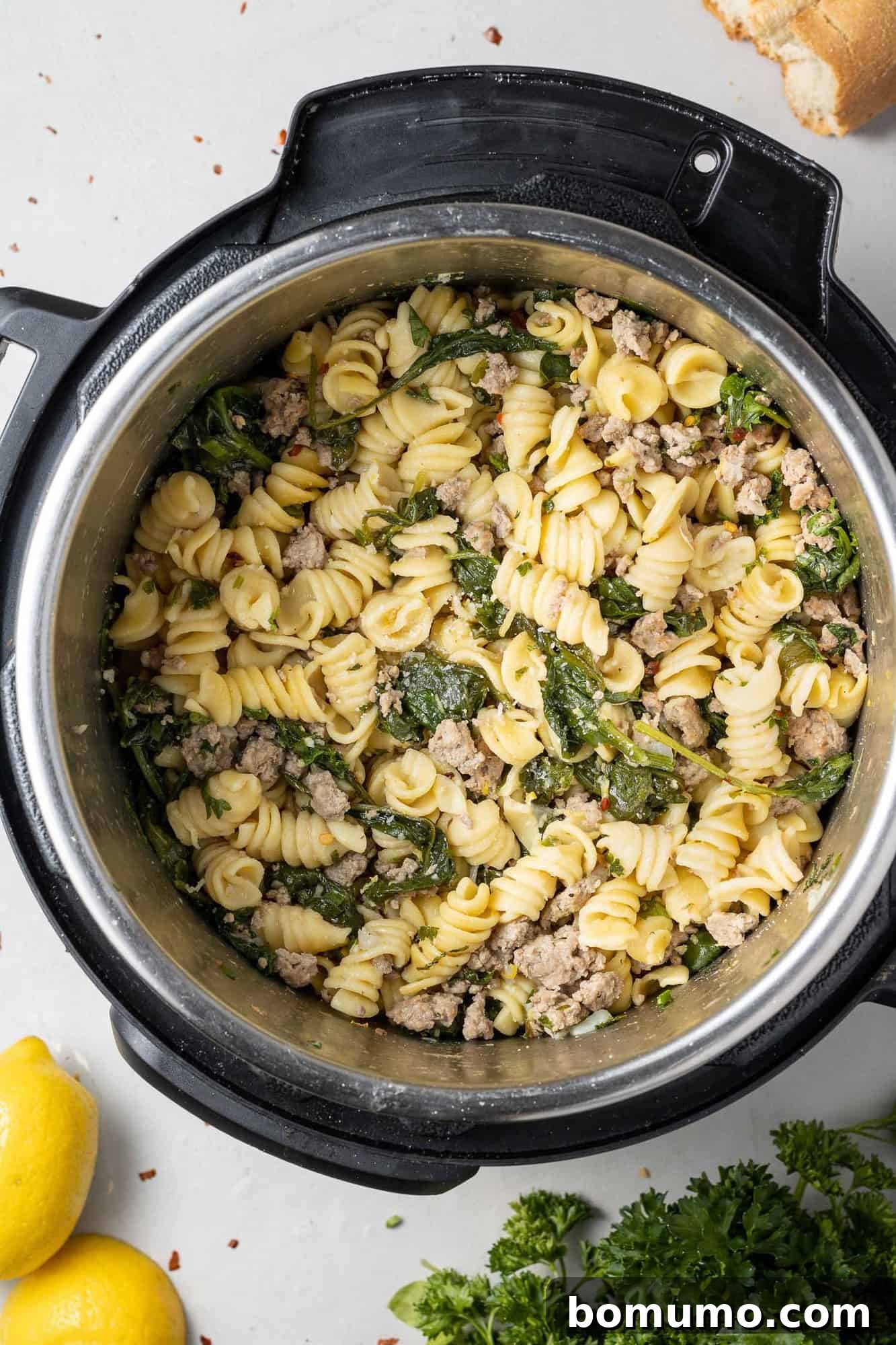 Overhead view of instant pot with pasta, spinach, and ground chicken.