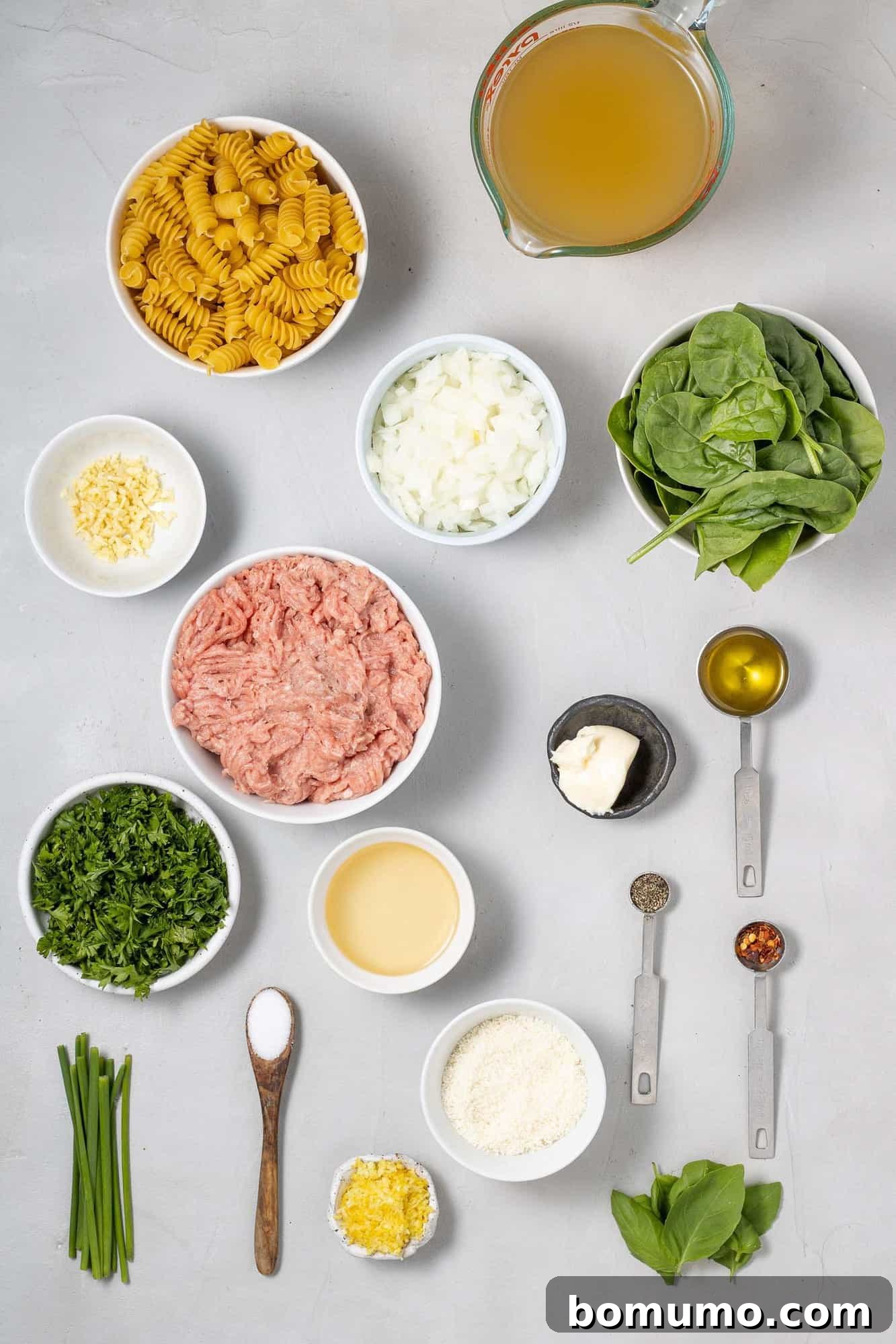 Overhead view of ingredients needed for recipe, including ground chicken, spinach, and lemon.