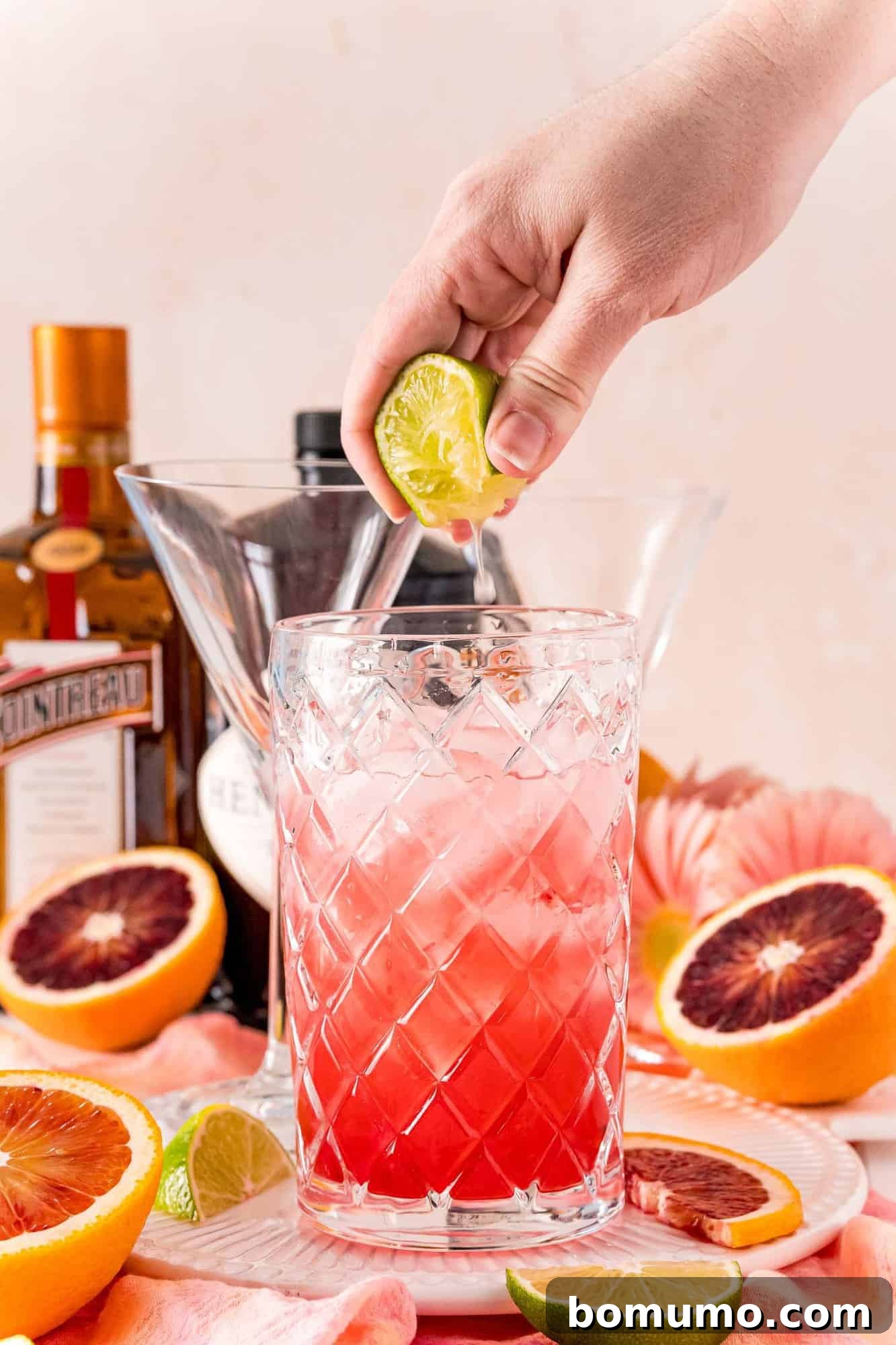 Blood Moon Martini 8 A hand expertly squeezing a fresh lime into a cocktail shaker, adding a vital touch of tartness to the mix.