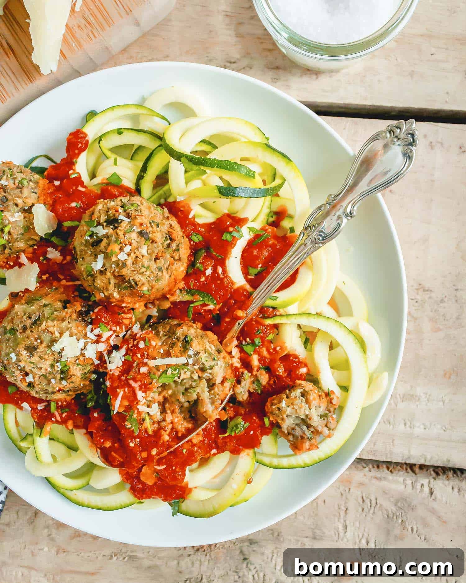 Overhead view of meatballs atop zucchini noodles, with spaghetti sauce.
