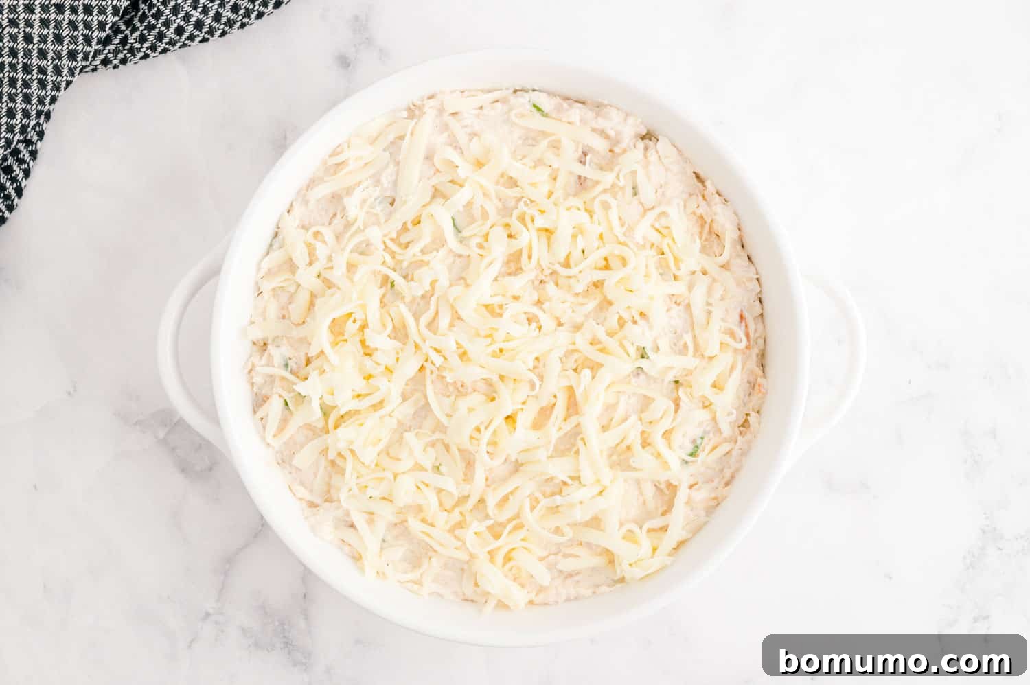 Unbaked dip in a round white baking dish.