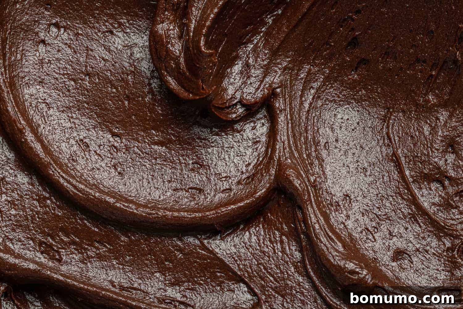Close up of chocolate frosting with elegant swirls, highlighting its smooth and rich texture.