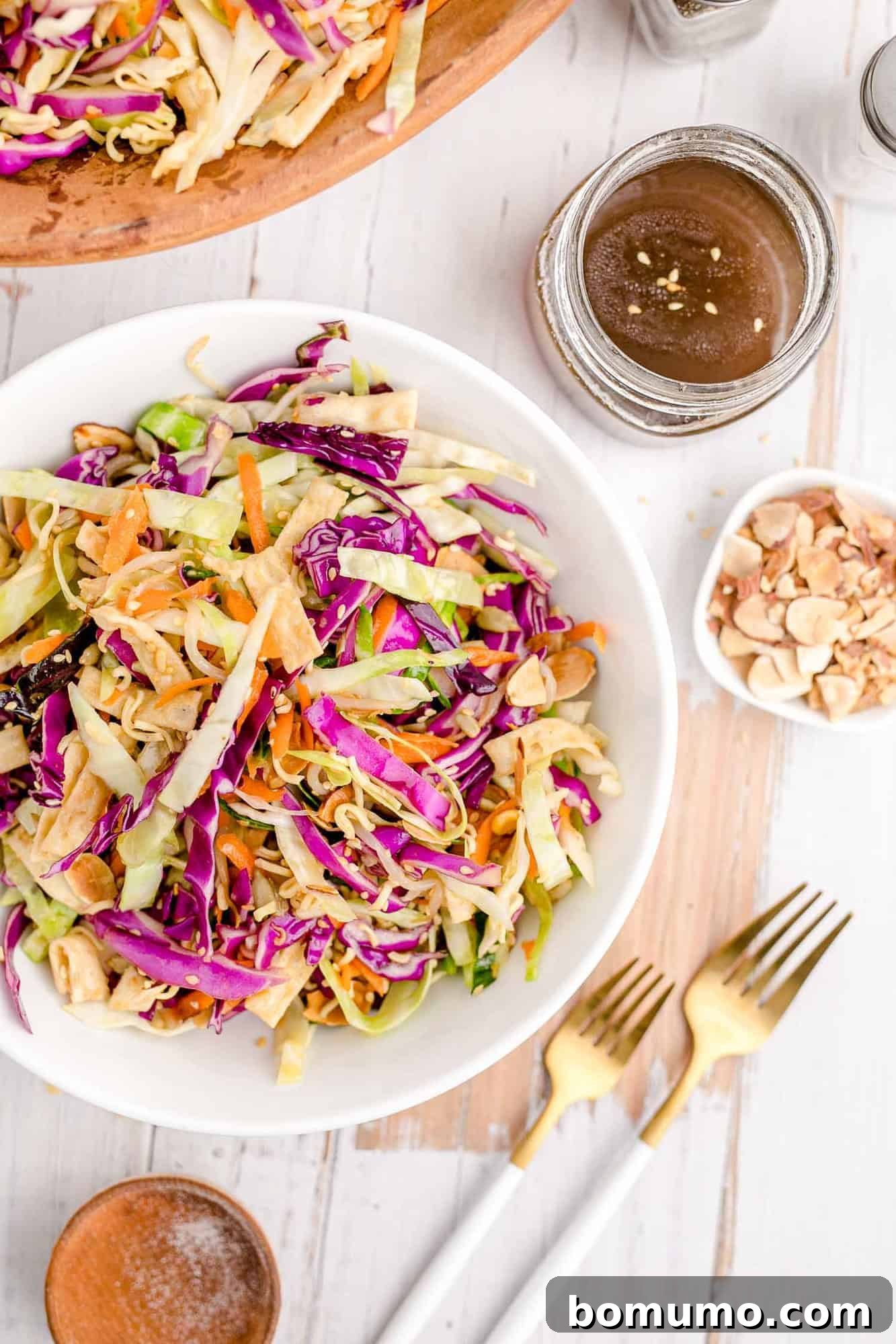 Overhead view of a cabbage based Asian style salad in a white bowl, showcasing vibrant colors and crunchy textures.