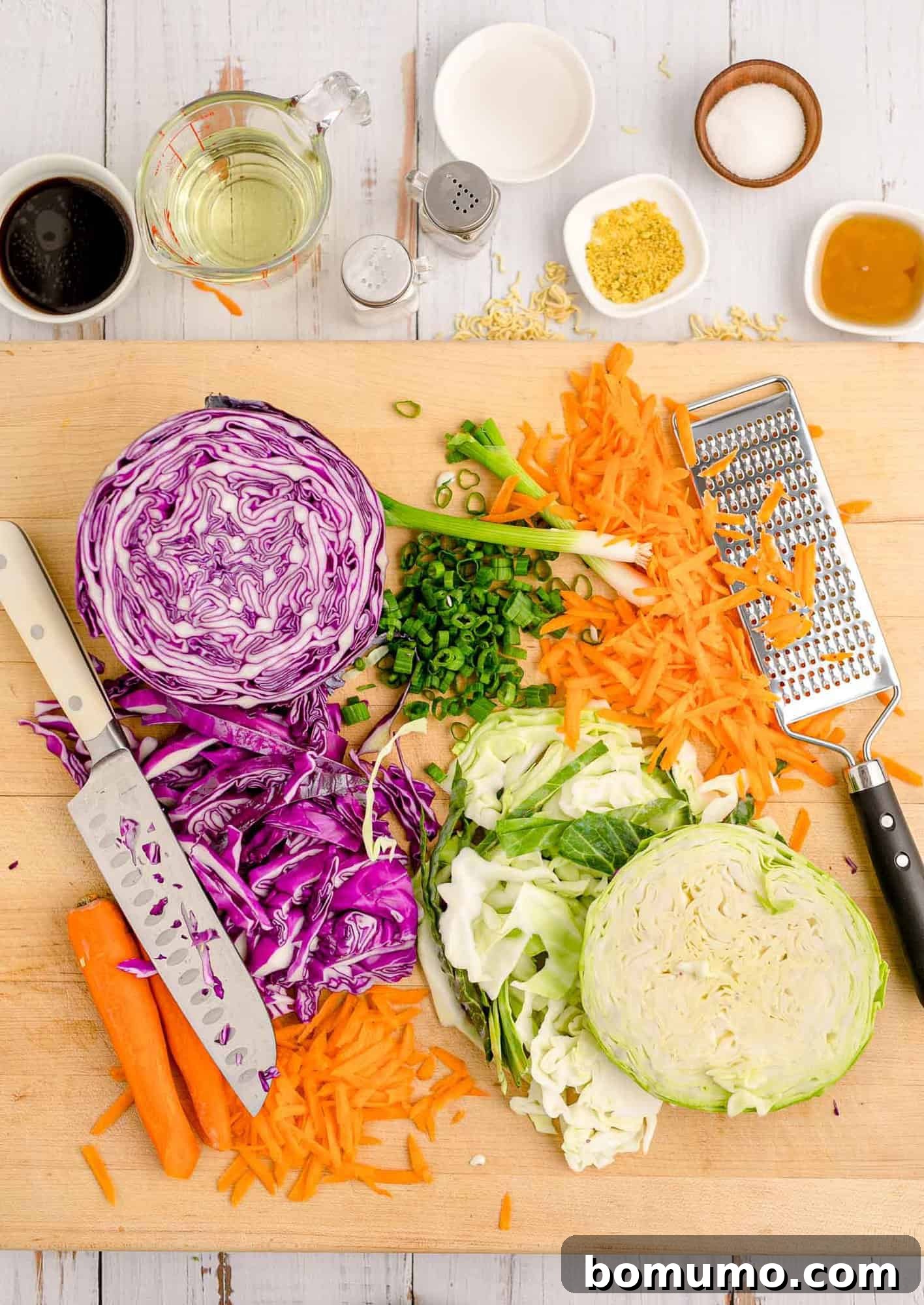 Shredded vegetables, a sharp knife, and a grater on a cutting board, illustrating the preparation process.