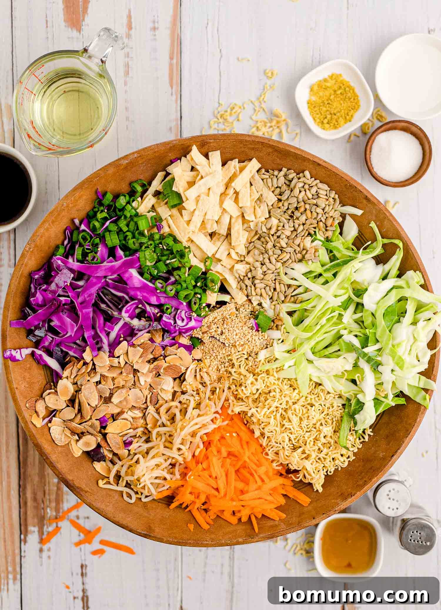 Unmixed fresh vegetables in a large wooden bowl, showcasing the colorful base of the salad.