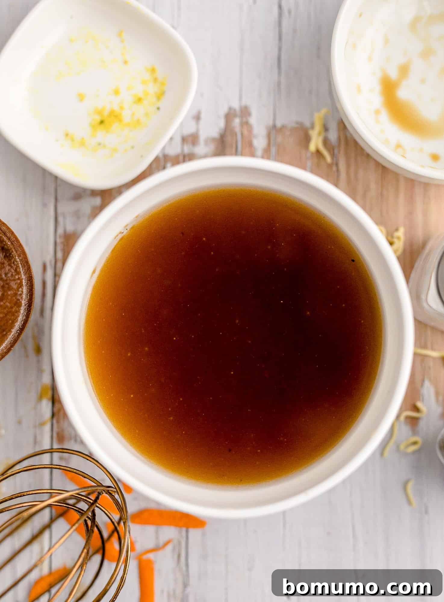Rich brown dressing in a white bowl, freshly mixed and ready to be poured over the salad.