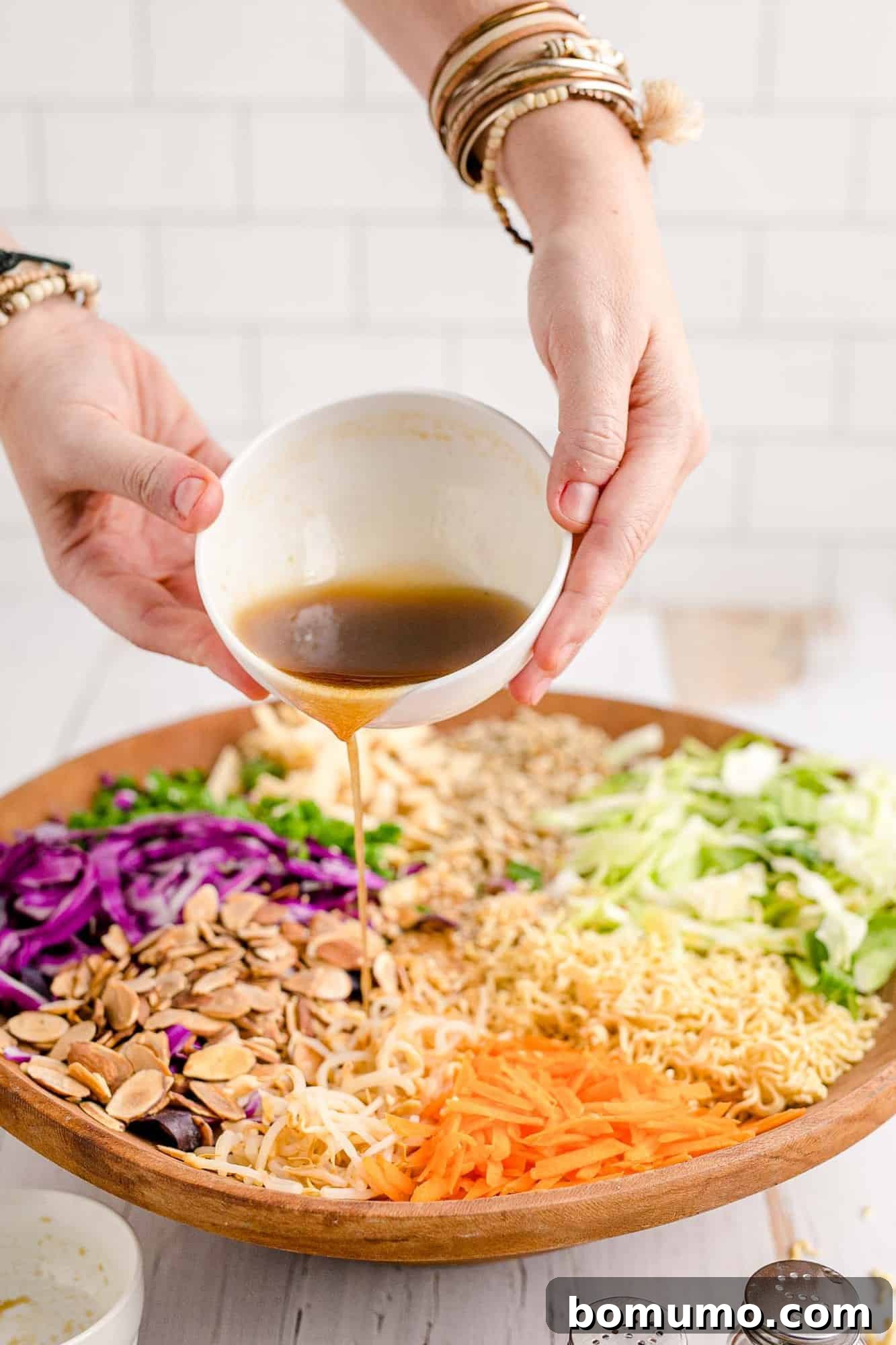 Dressing being poured over a large salad, demonstrating the final assembly step before tossing.