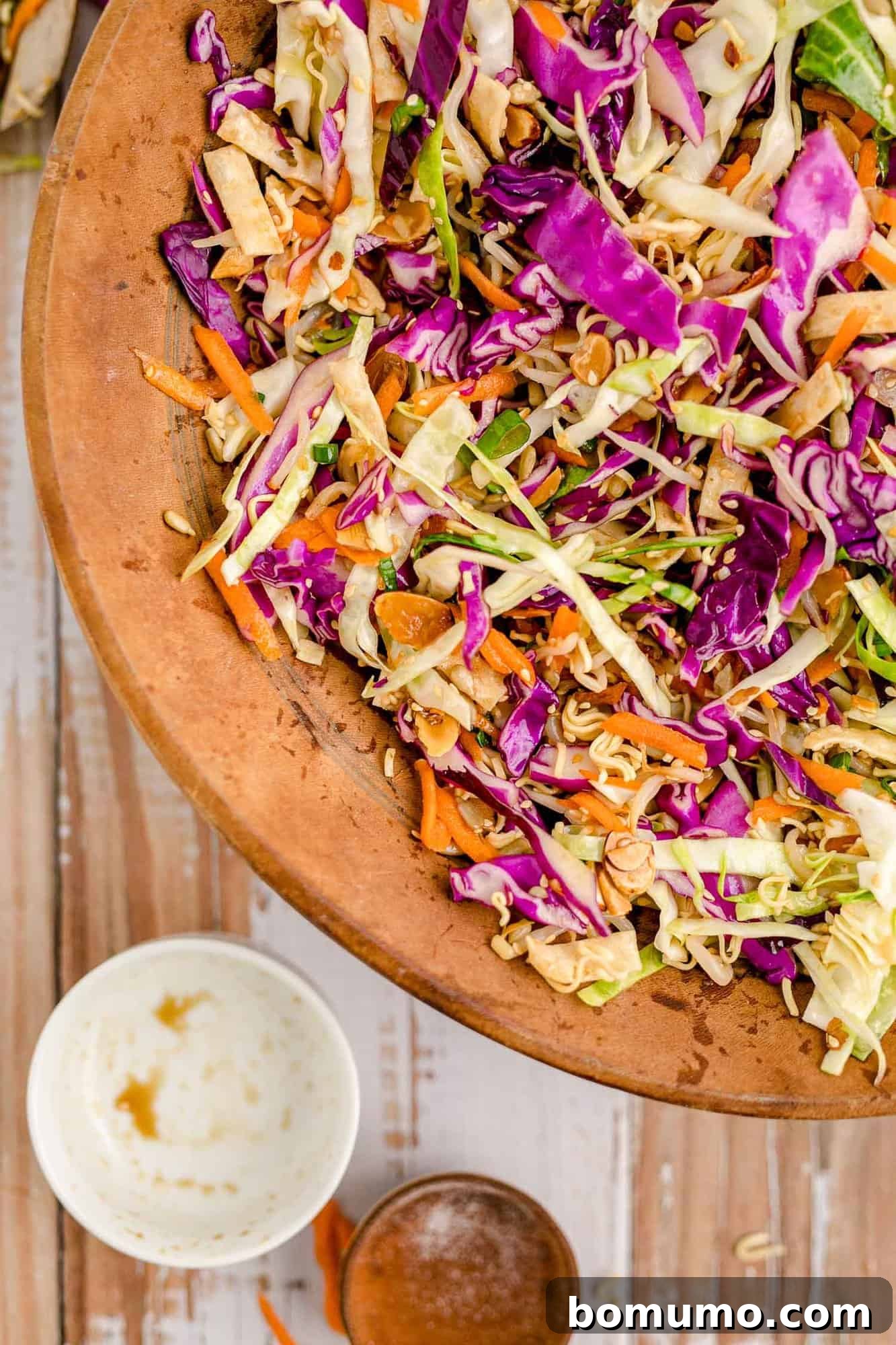 Close up of Asian salad in a wooden bowl, highlighting the vibrant colors and varied textures of the ingredients.