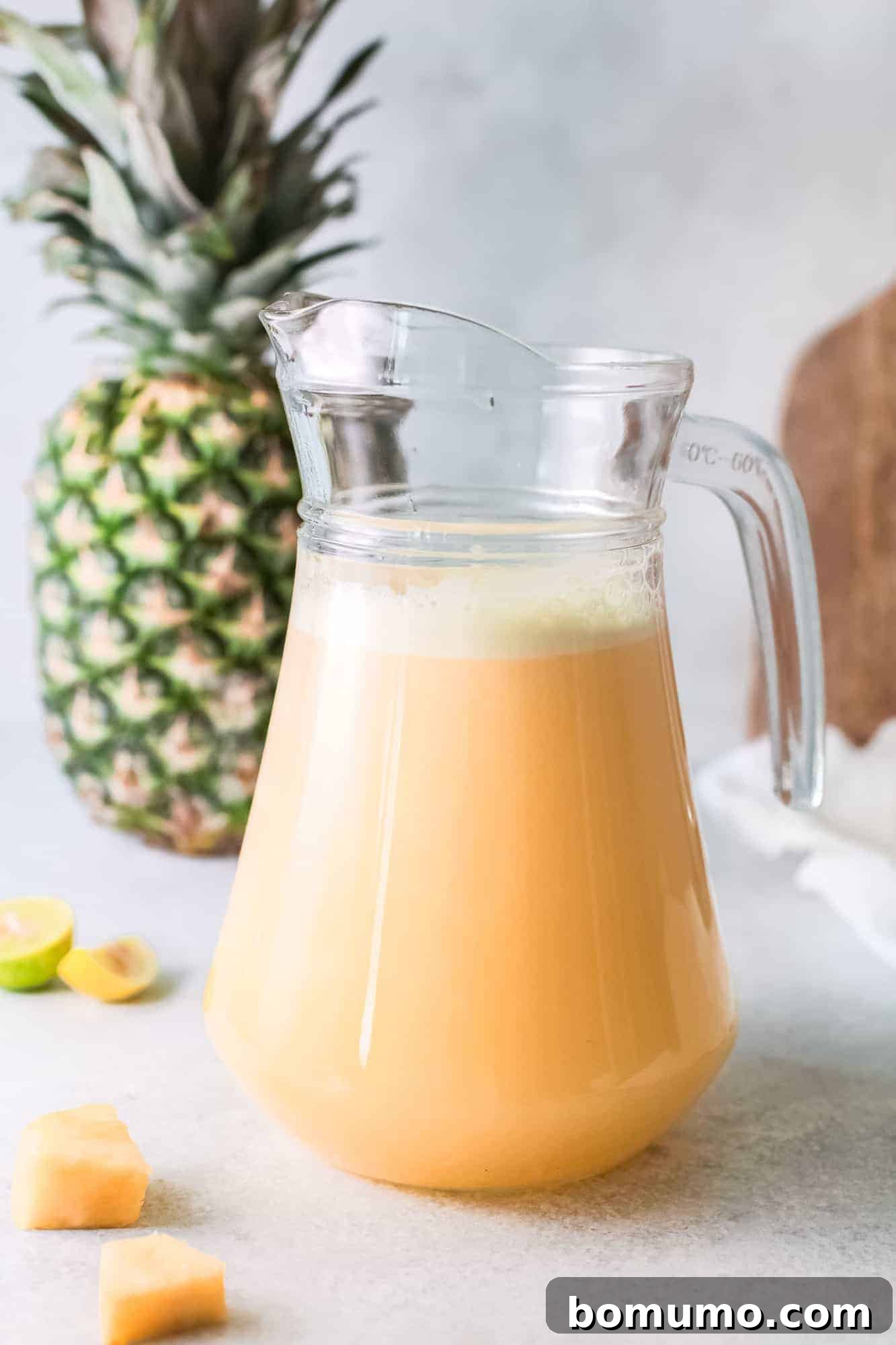 Pineapple Agua Fresca 6 Pineapple water in a pitcher, with a large pineapple in the background, ready for chilling.
