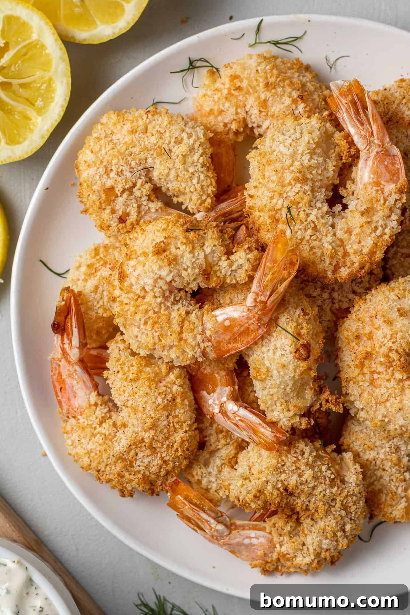 A generous serving of crispy air-fried breaded shrimp piled high on a clean white plate, showcasing their inviting golden hue.