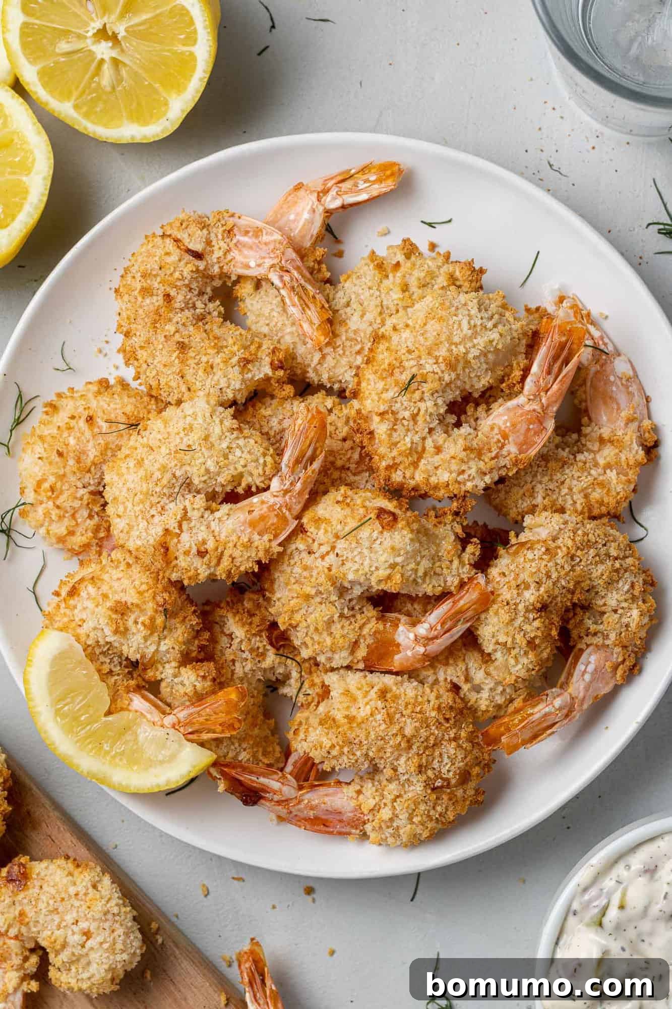 A beautifully cooked pile of golden-brown air fryer breaded shrimp, presented on a white plate, highlighting their appetizing crispiness.
