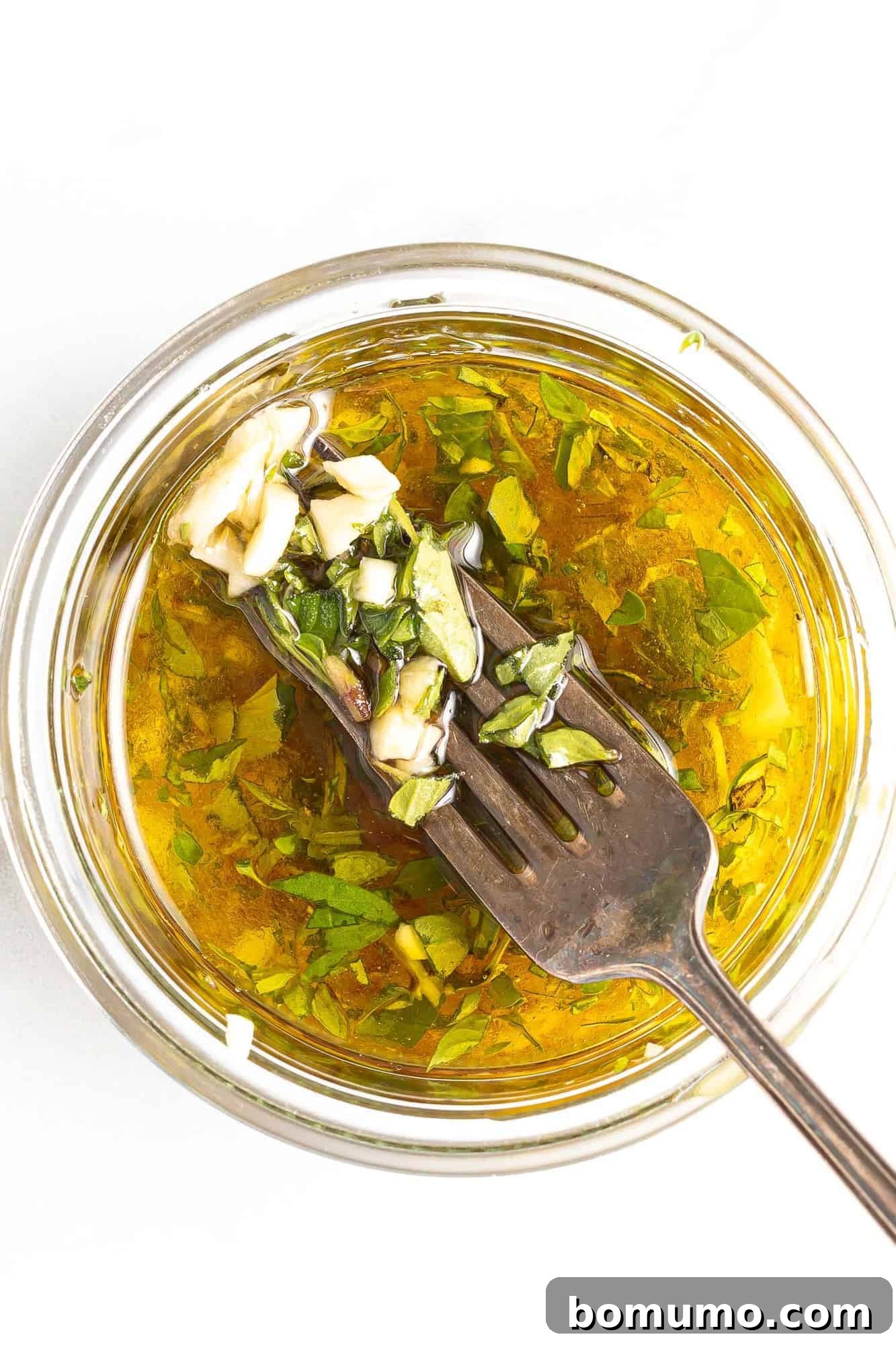 Dressing in a jar with a fork showing some ingredients.