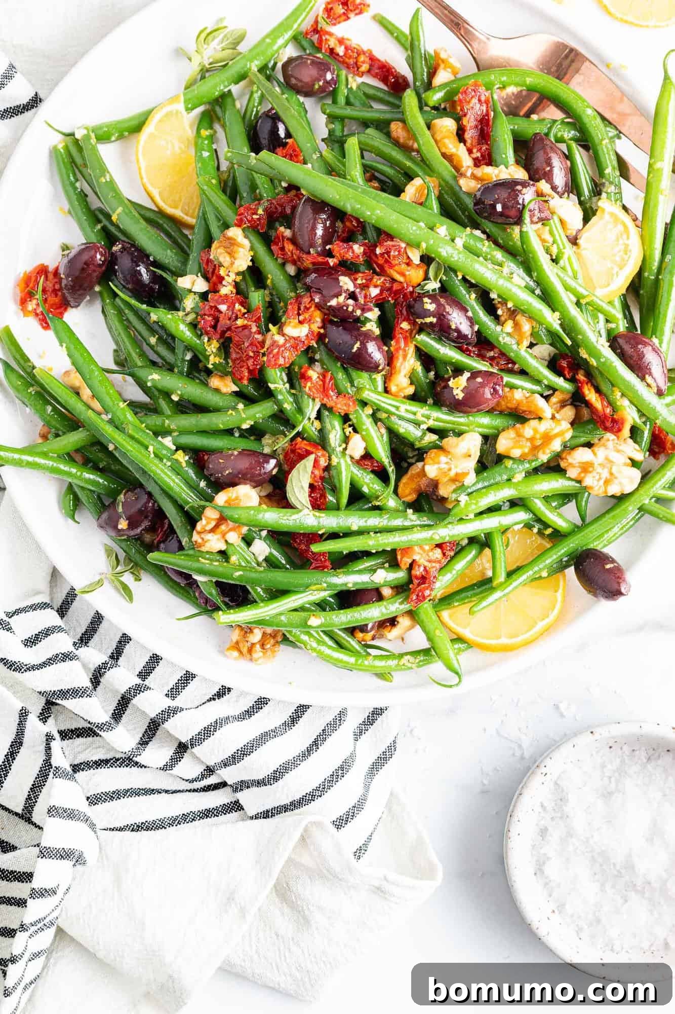 Overhead view of colorful green bean salad with lots of mediterranean inspired toppings.