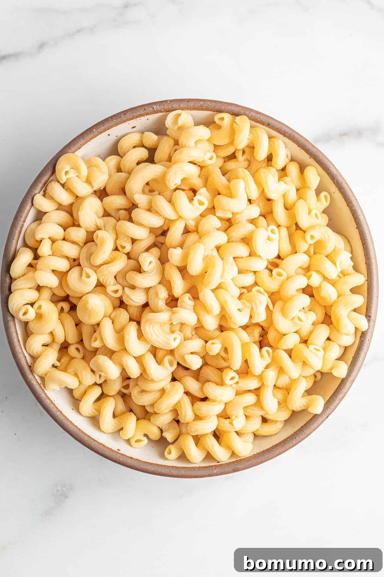 Perfectly cooked pasta, freshly drained and ready to be combined with the baked feta sauce, resting in a large bowl.