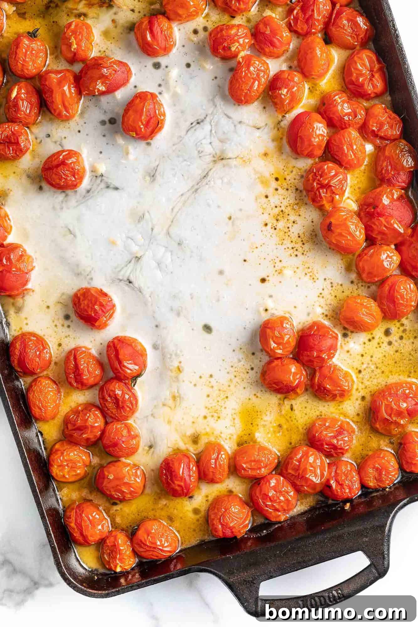 Melted feta cheese and perfectly roasted cherry tomatoes mashed together in a baking dish, forming a rich and creamy pasta sauce.