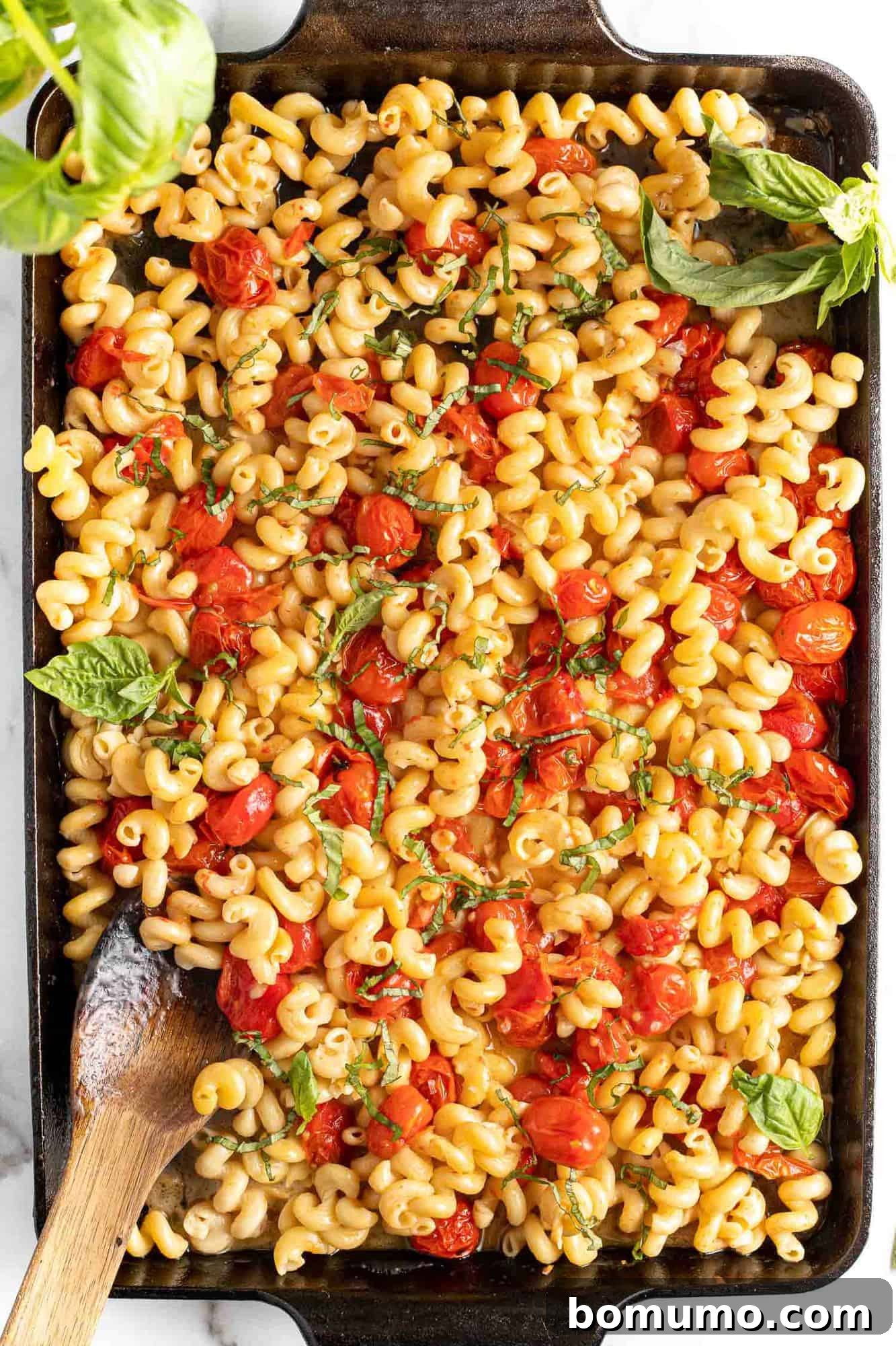A close-up of the finished baked feta pasta, rich with tomatoes and feta sauce, beautifully garnished with fresh basil.