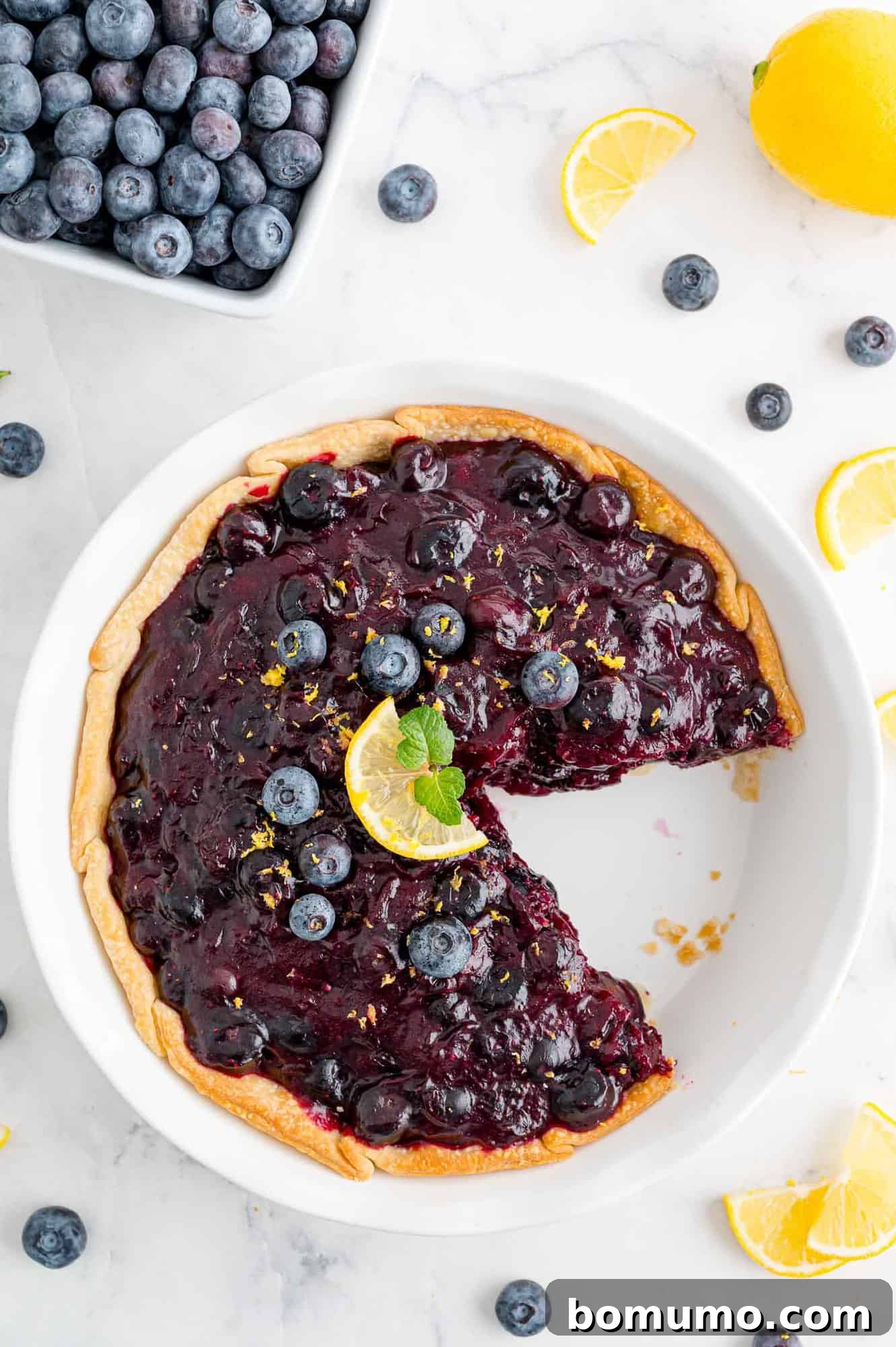blueberry-pie-with-text Overhead view of fresh blueberry pie with a slice removed.